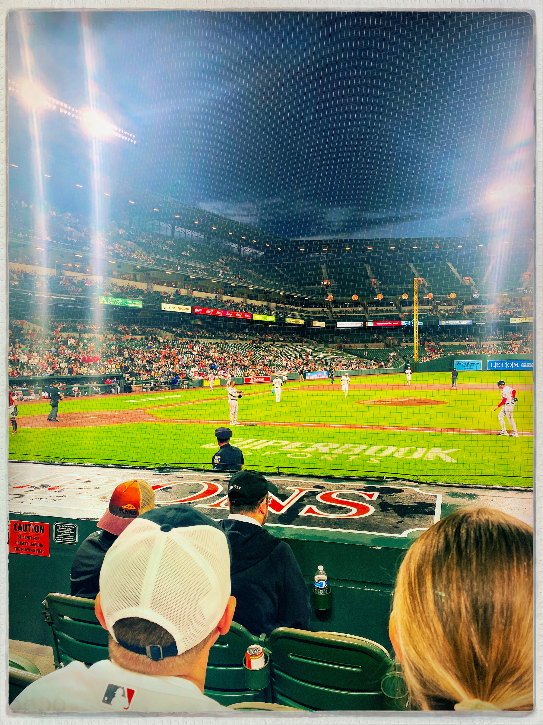 A baseball game is underway at a well-lit stadium, with players on the field and spectators watching from the stands.
