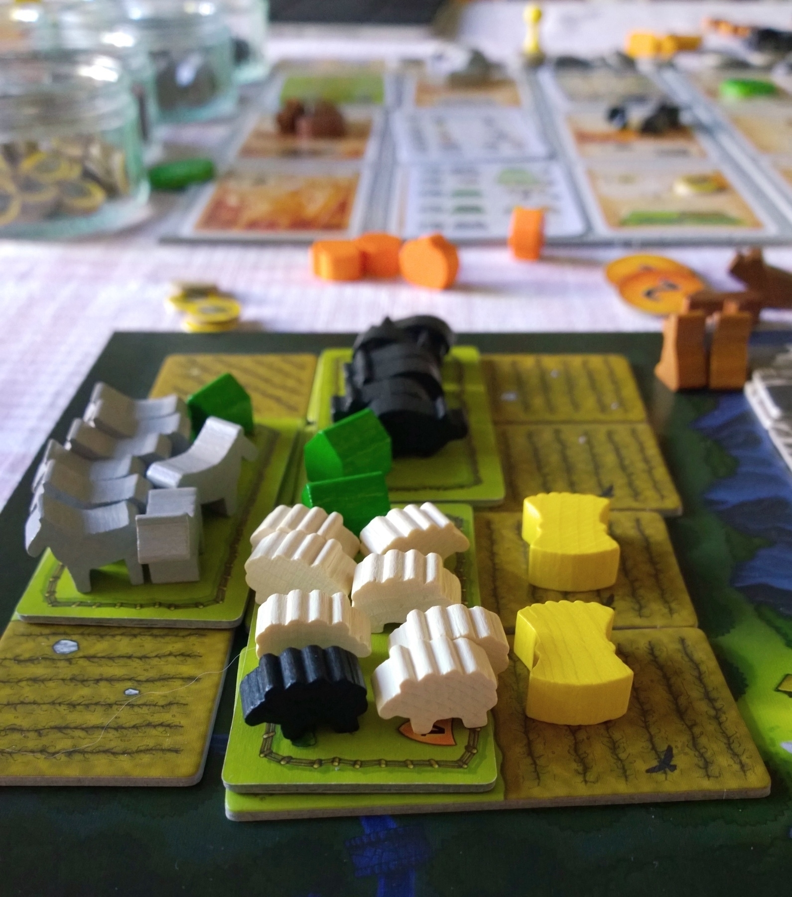 close up view of part of a player board in Caverna board game showing sheep pigs wheat and other items 
