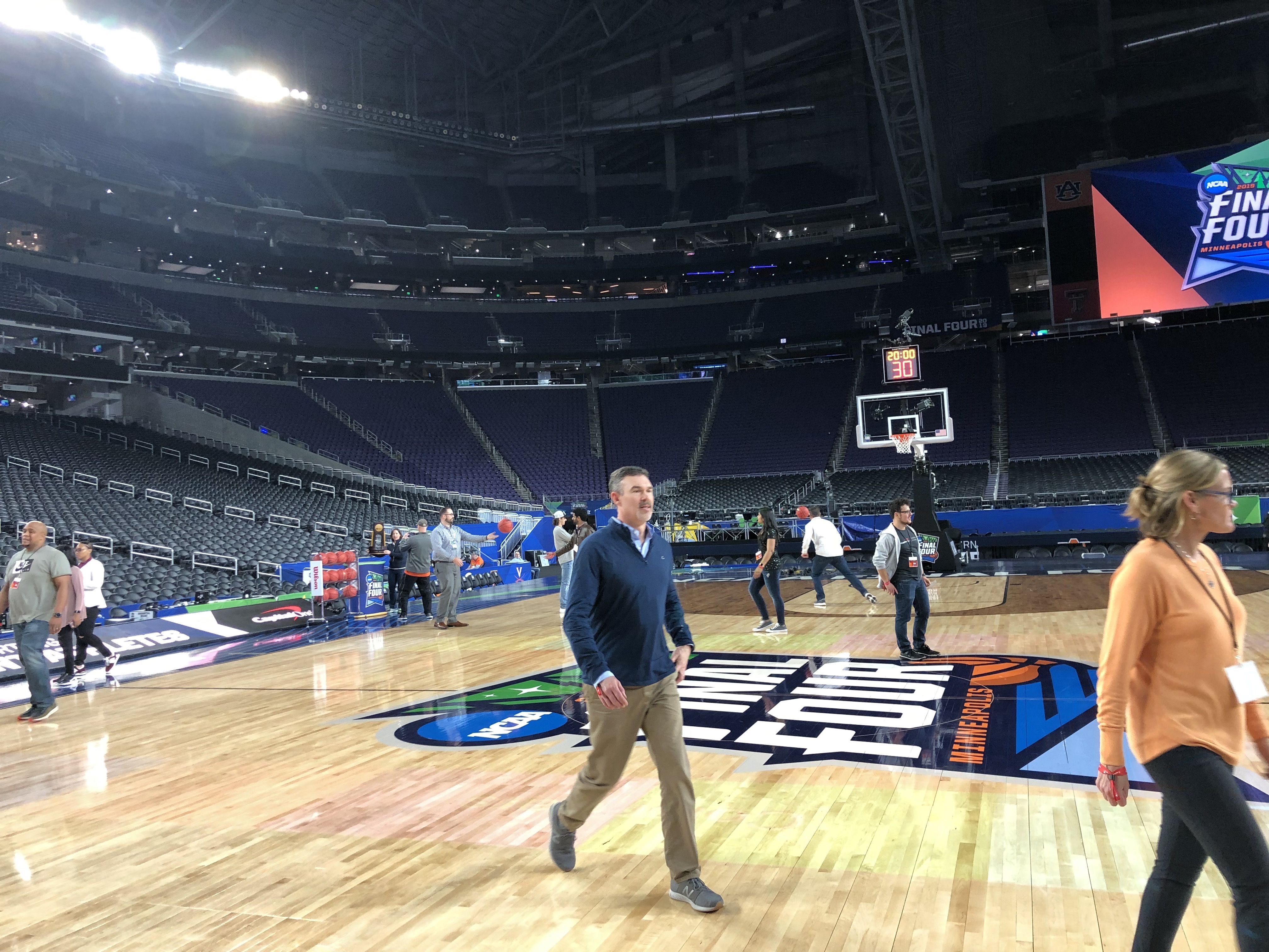 Peple on the basketball court the night before the Final Four games. Empty stadium otherwise.