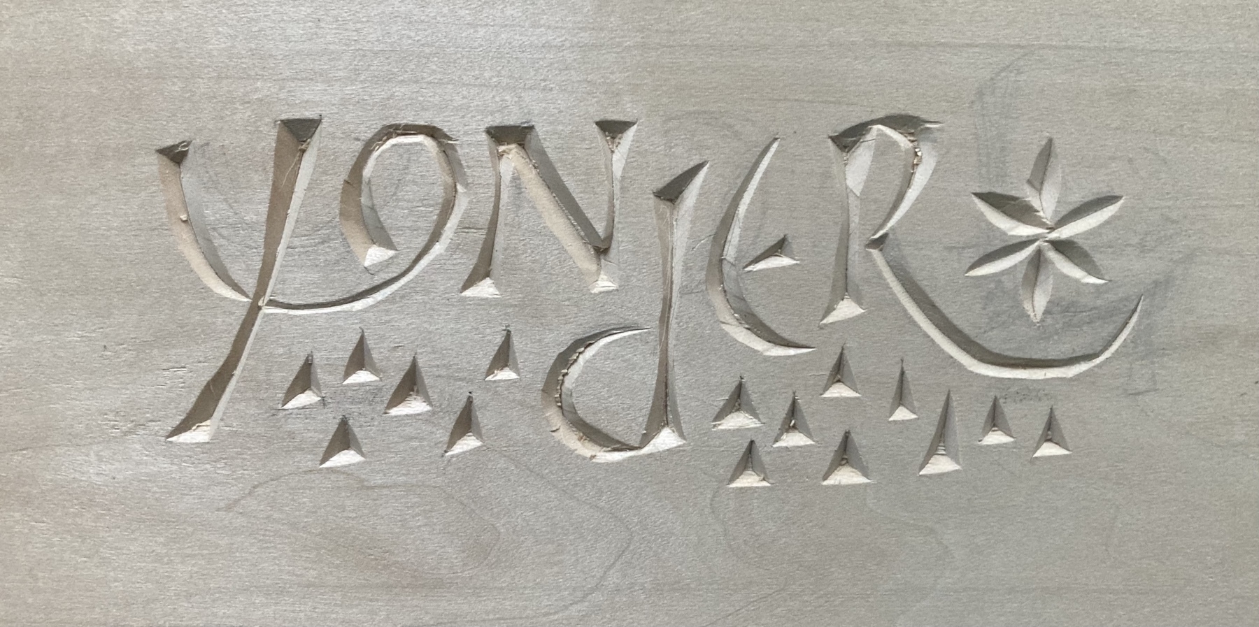 chip carving of the word yonder with triangles to represent mountains