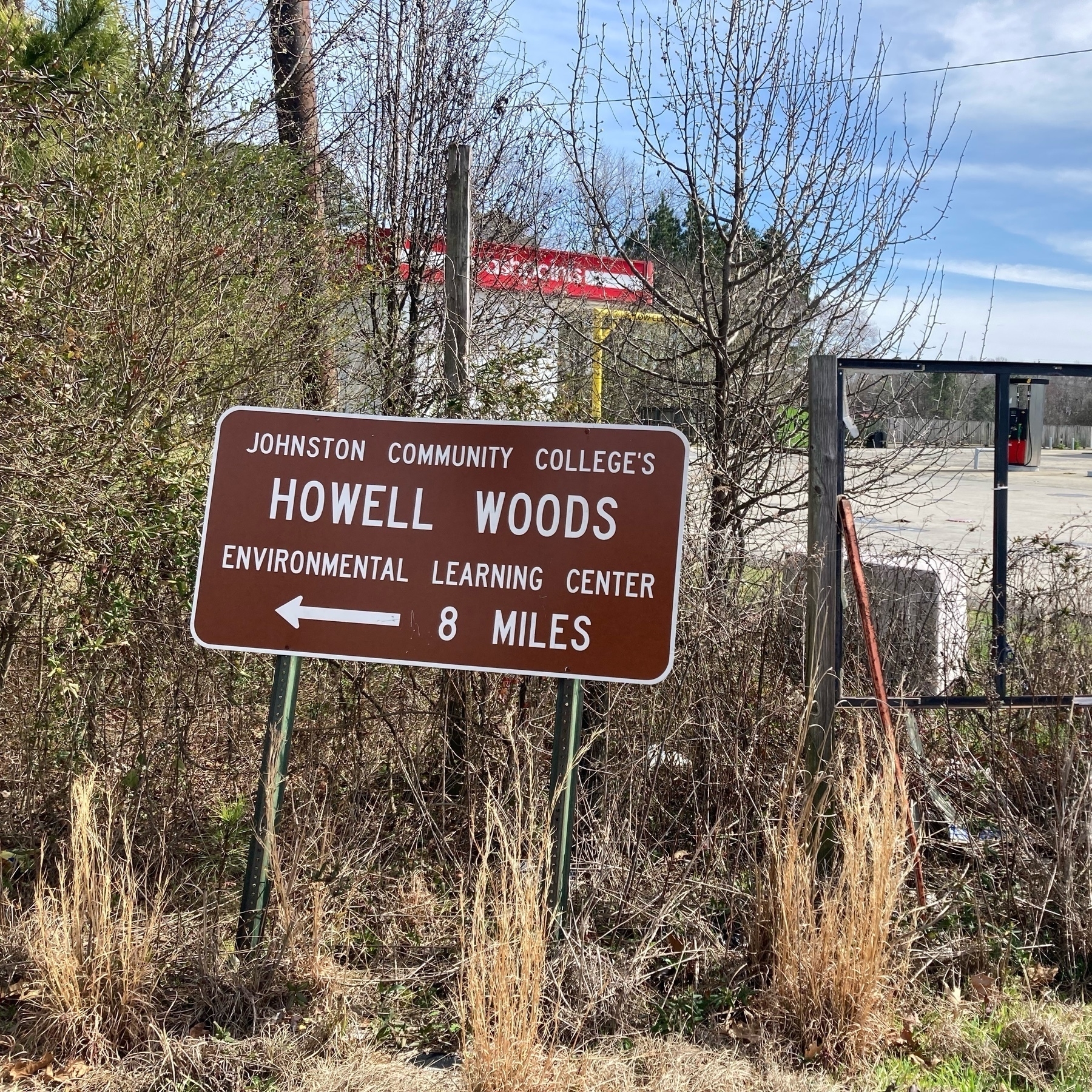 sign with atrow saying Howell Woods Environmental Learning Center 8 miles