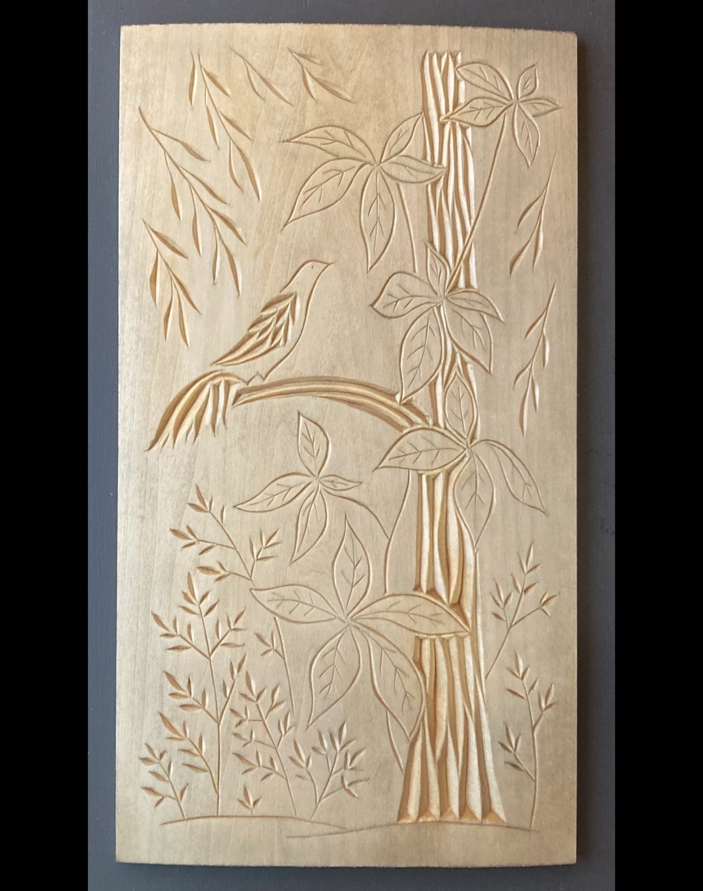 chip carving of Virginia creeper vining on a tree, with a bird, sheltering branches and underbrush