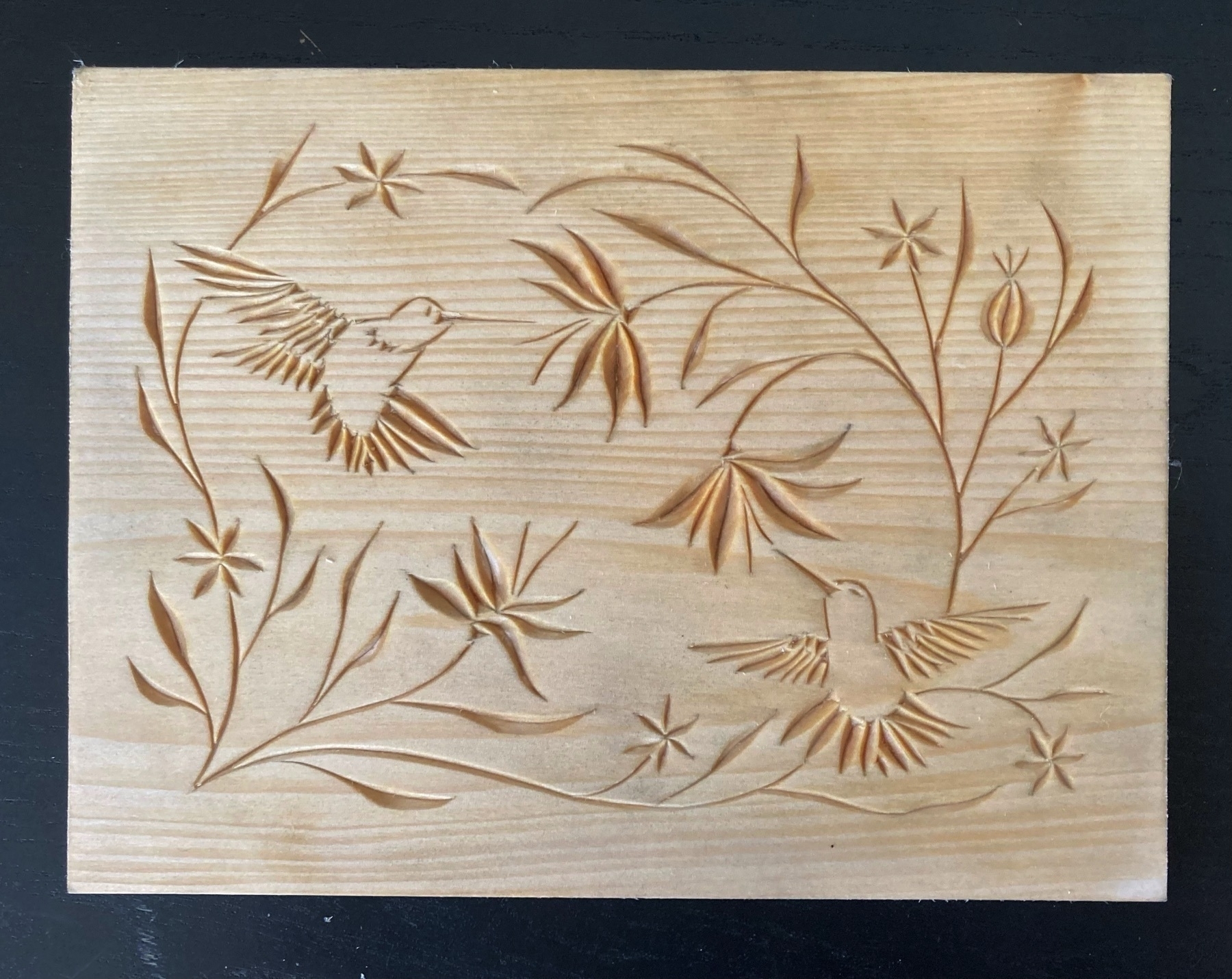 chip carving of two hummingbirds in a swirl of flowers