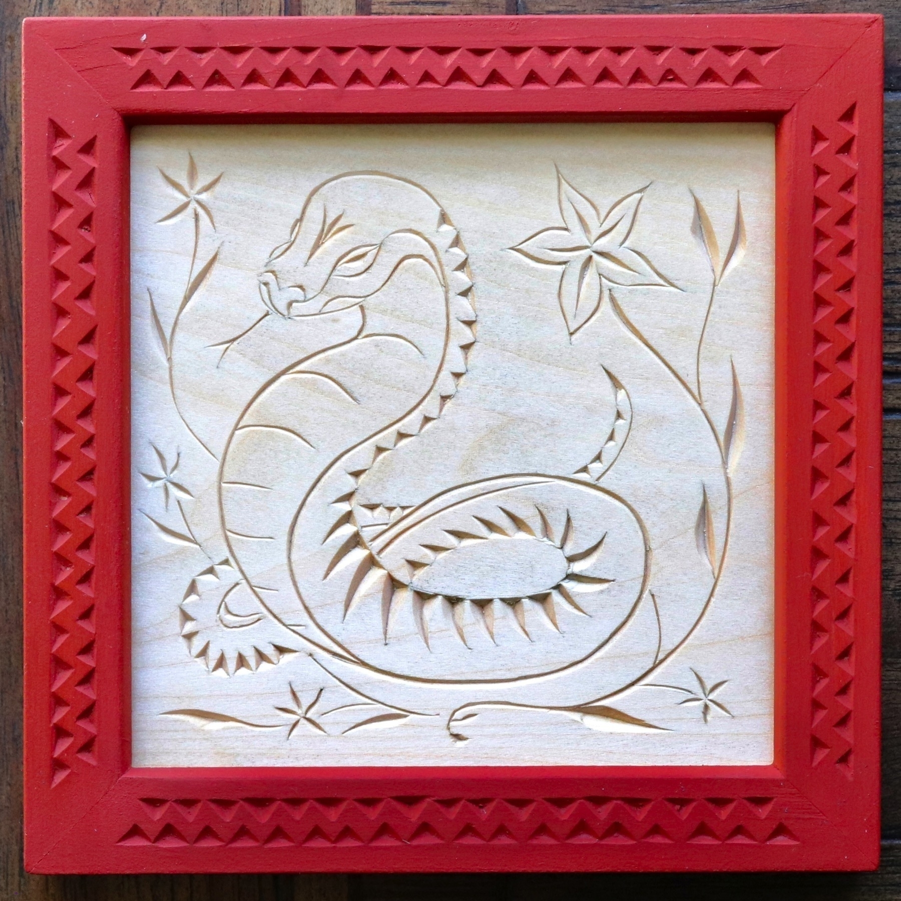 chip carving of Chinese-styled snake with five-petal flowers, carved red frame