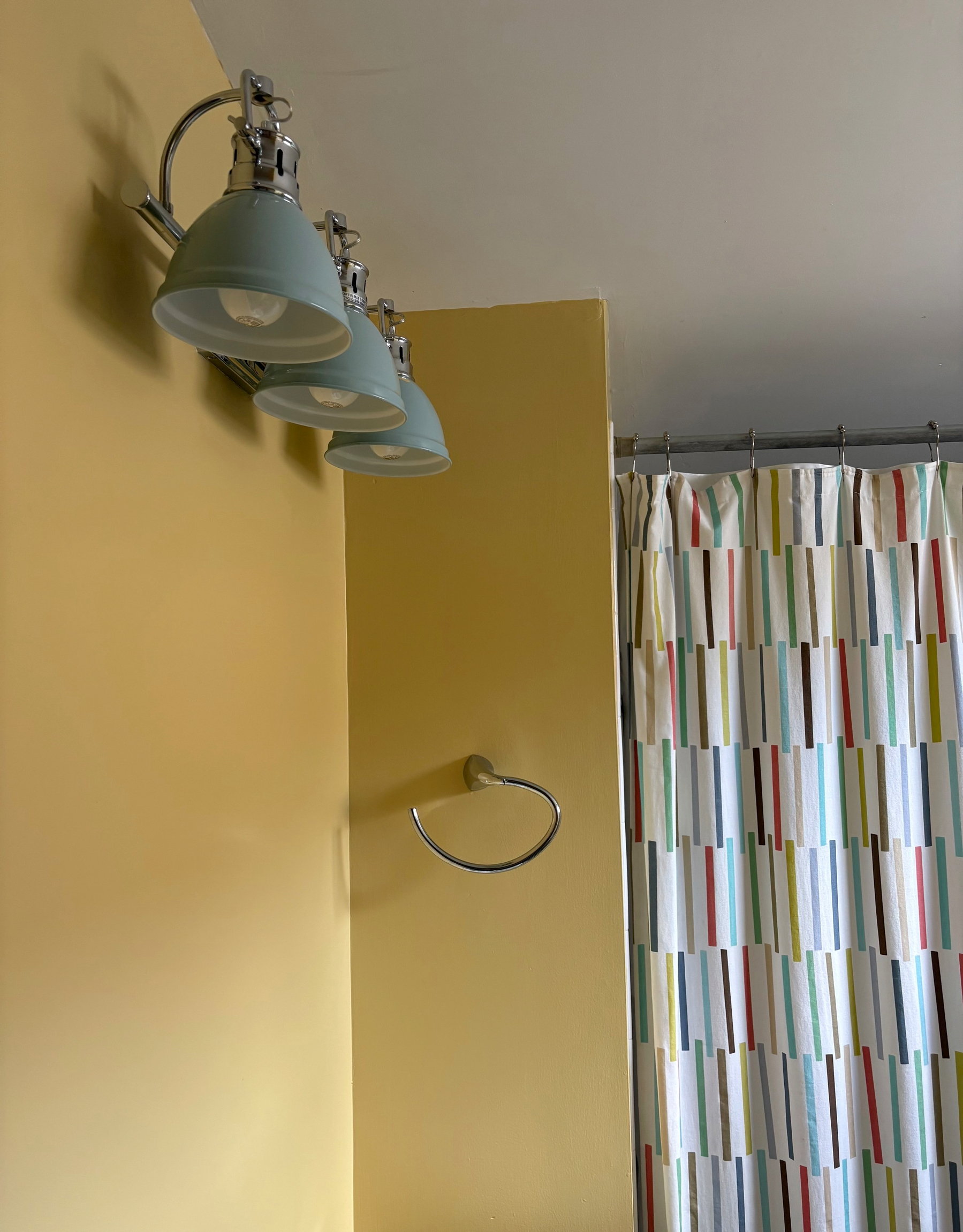 my bathroom is “dirty yellow” with aqua blue vanity lamps and a multicolor striped shower curtain