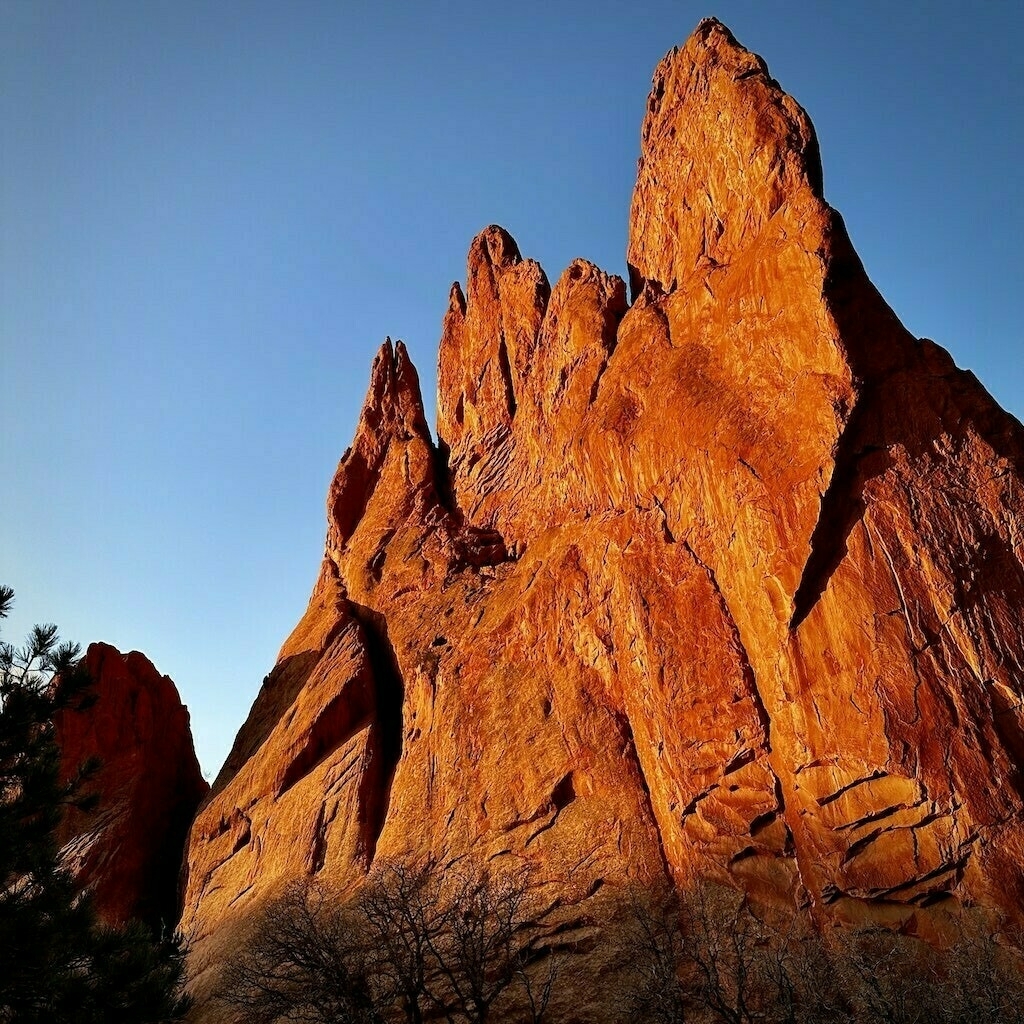 Sun shining on red rock from Garden of the Gods park. Blue sky. 