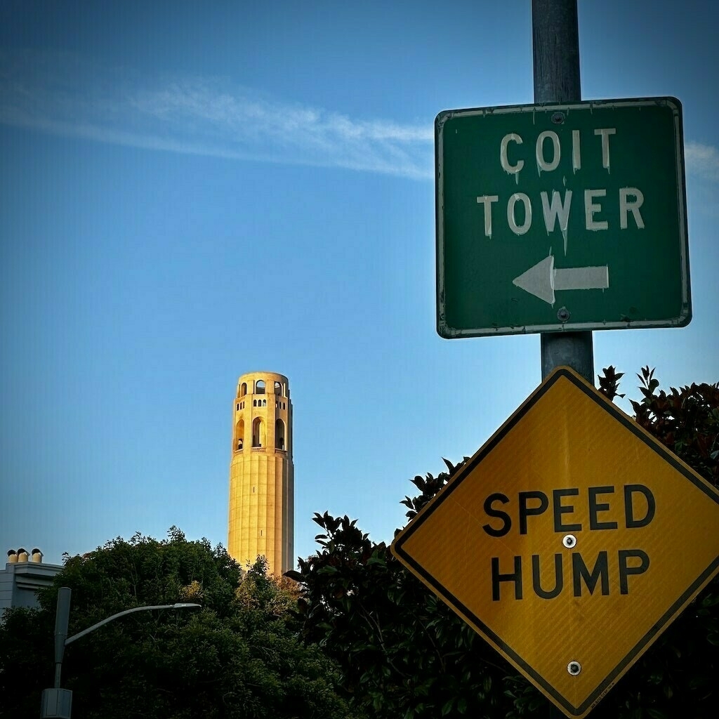 Coit Tower with blue sky and street sign saying "Coit Tower."