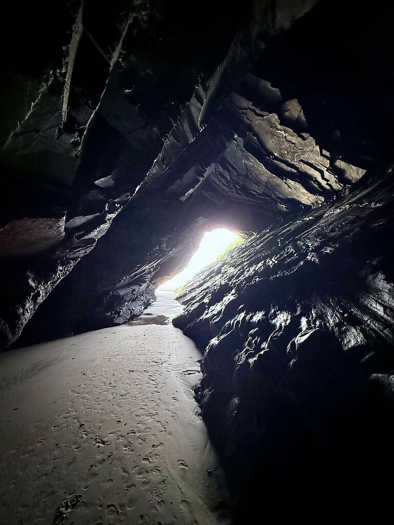 Looking out from a natural cave on a beach at a bright sunny day via a small opening