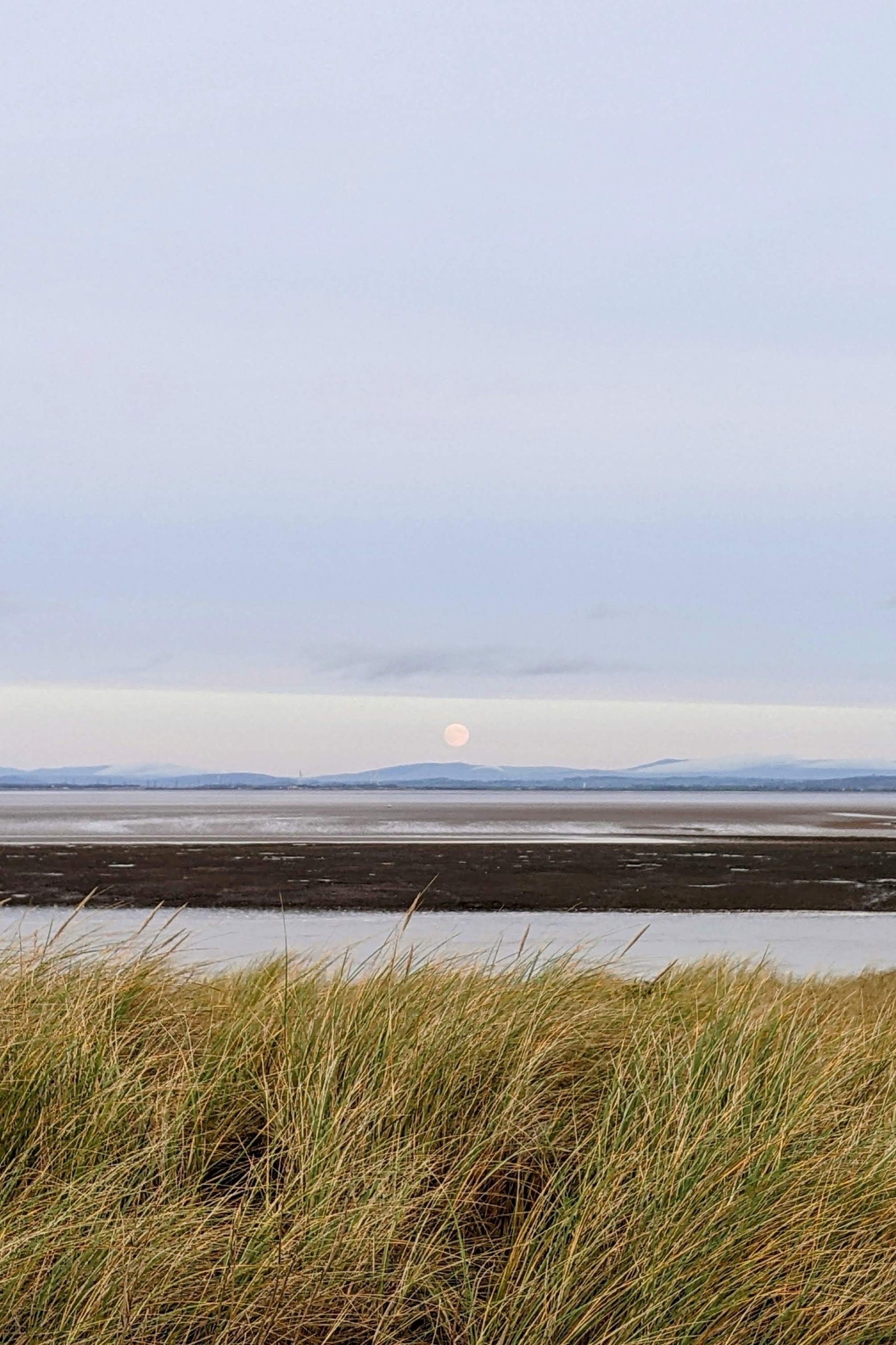Big full moon rising on the horizon over the distant hills of the Lake District