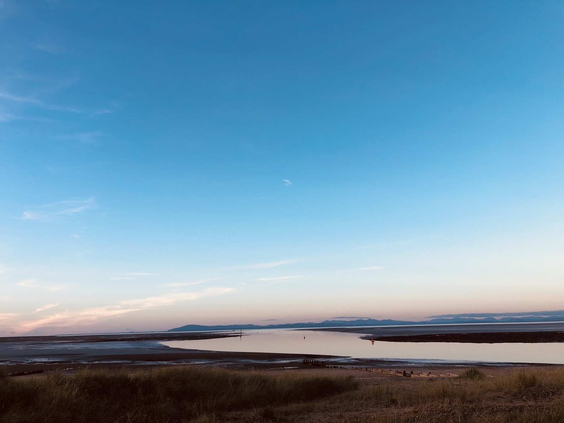 View of curving estuary at low tide and distant Lake District hills at dusk