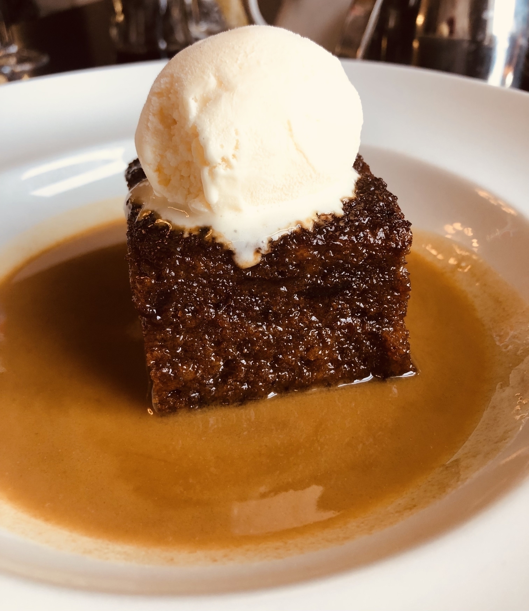 A bowl of sticky toffee pudding with icecream