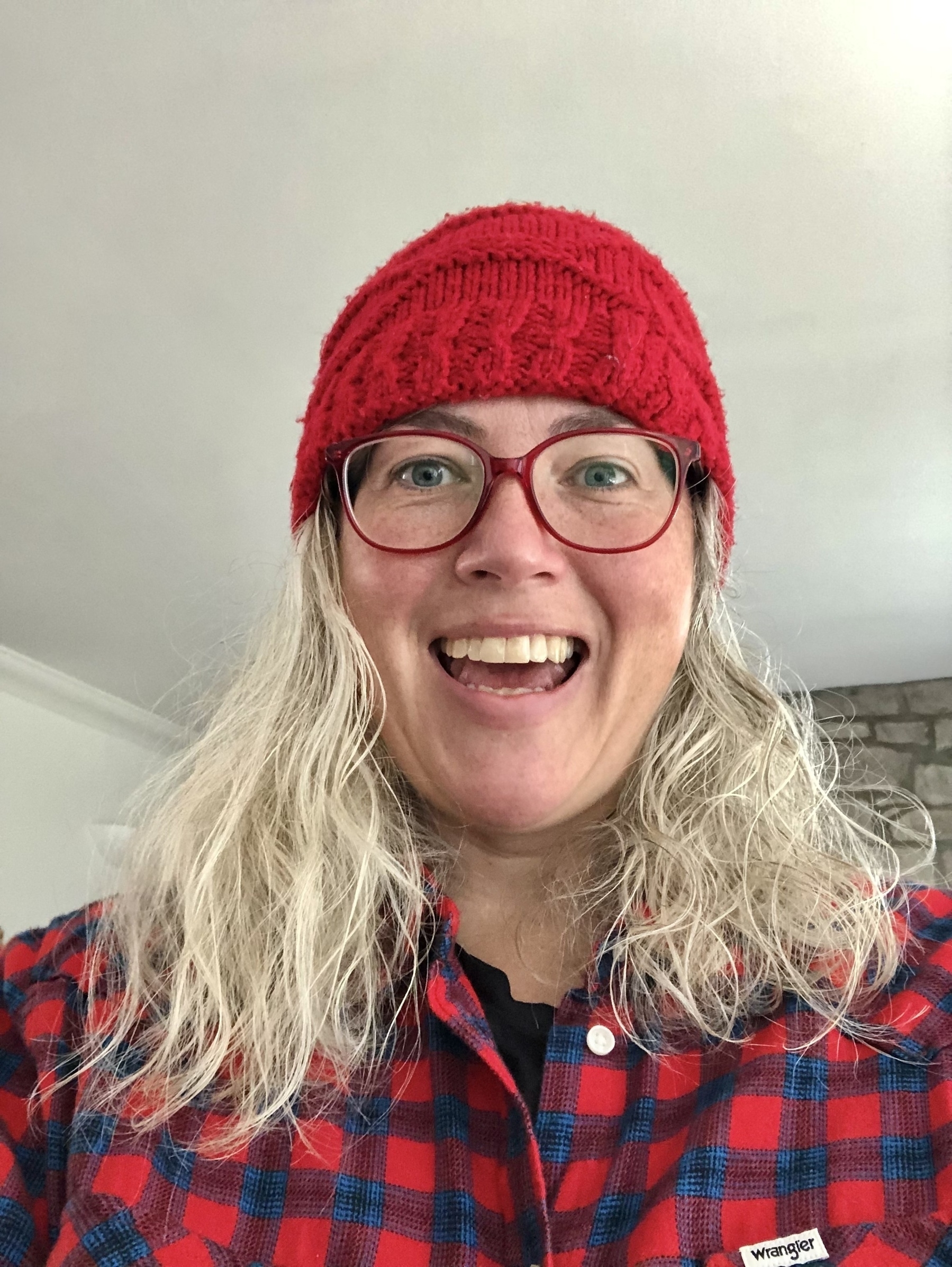 woman with red bobble hat and glasses on gasping at camera in surprised disbelief