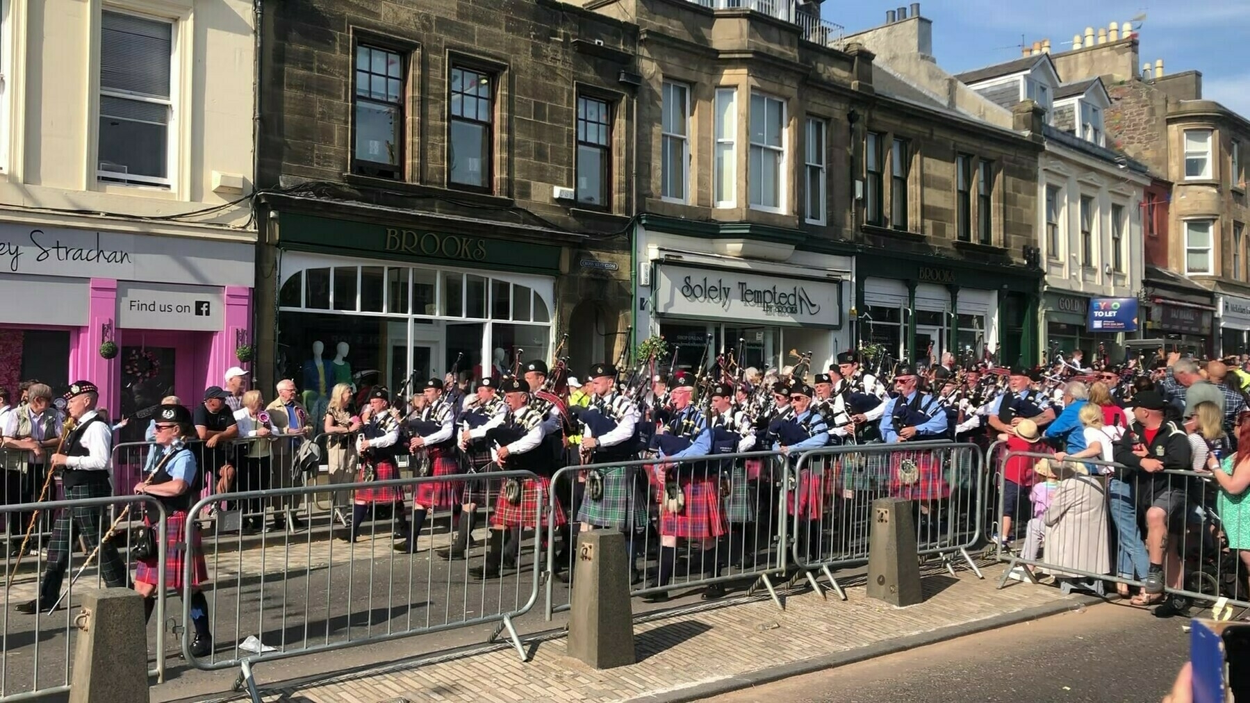 Bagpipe band marching along the street in Scotland. Lot's of lovely kilts!
