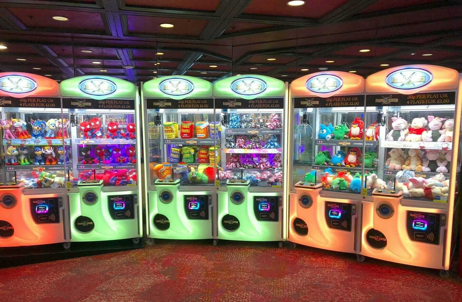 bright, colourful crane machines sitting in a row in an arcade