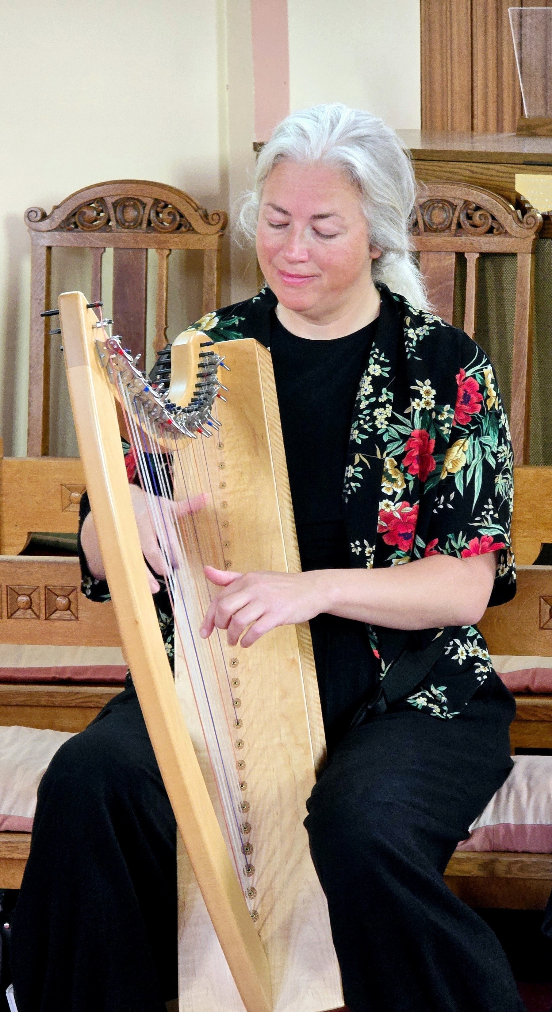 Lady sitting on a pew, in church playing the harp