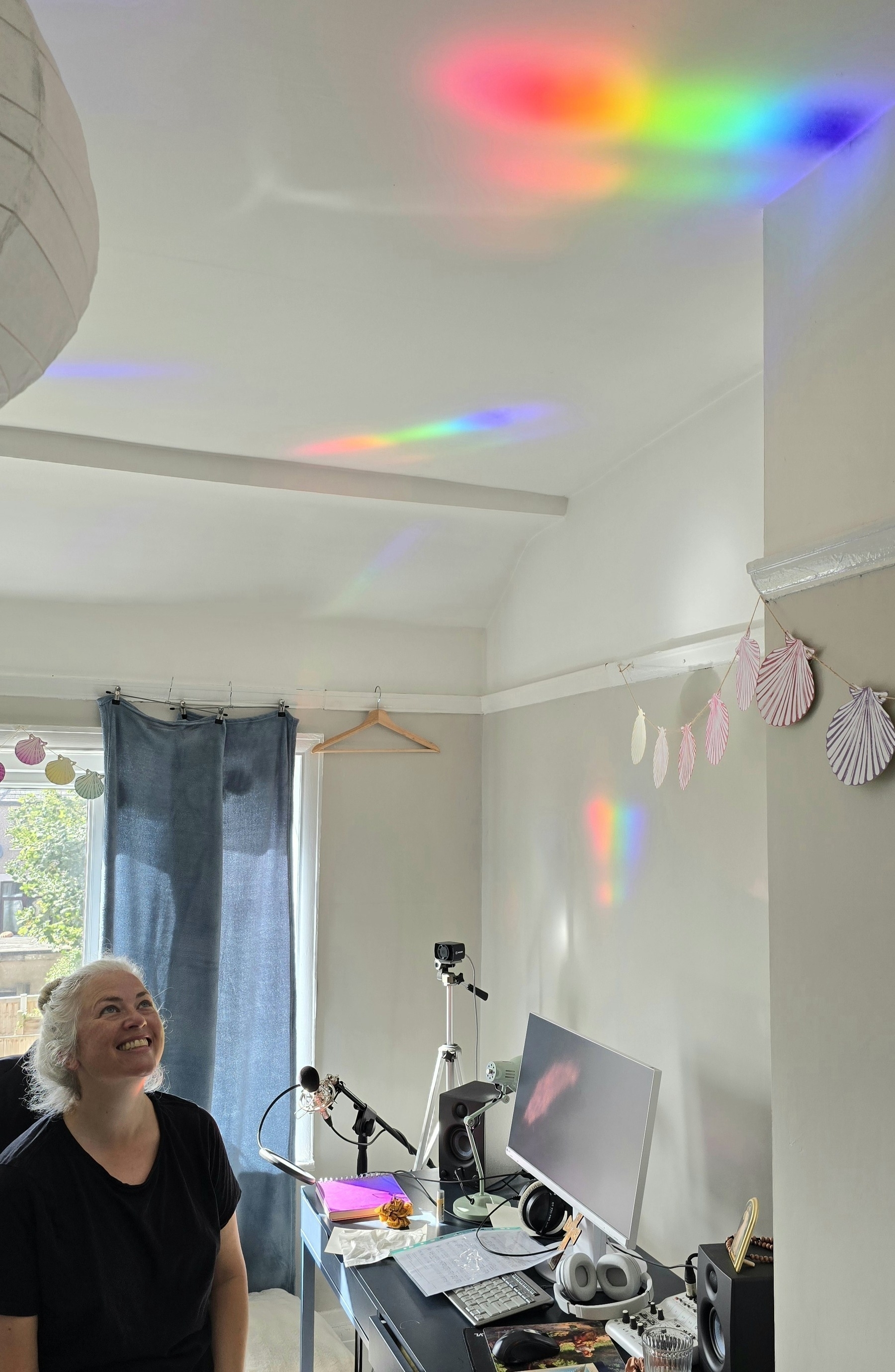 Woman sitting in a music studio with bright holographic rainbows on the walls. 