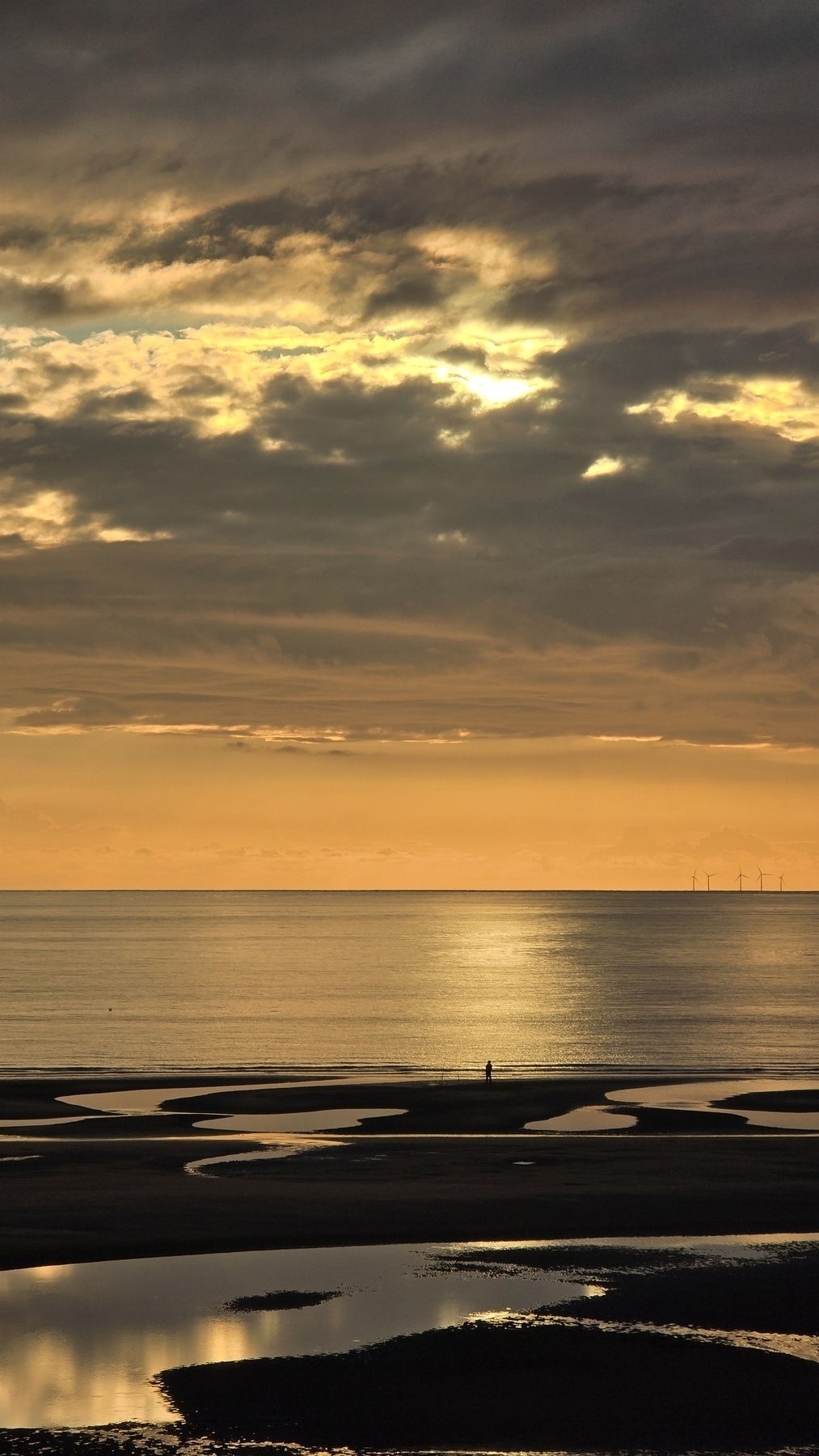 Orange cloudy sky over a shimmering, golden sea