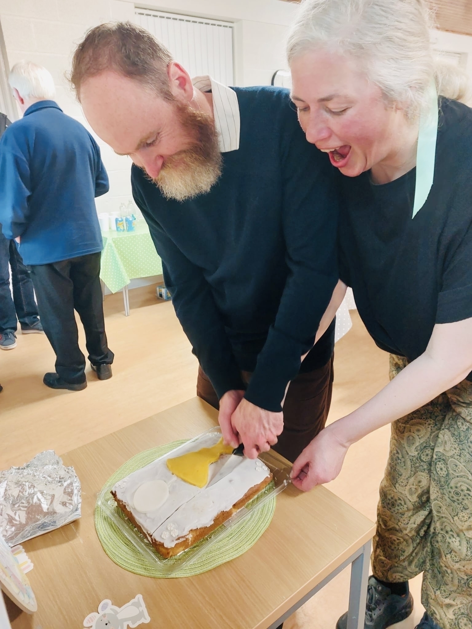 Holly and Simon cutting into a cake, happy and joyful
