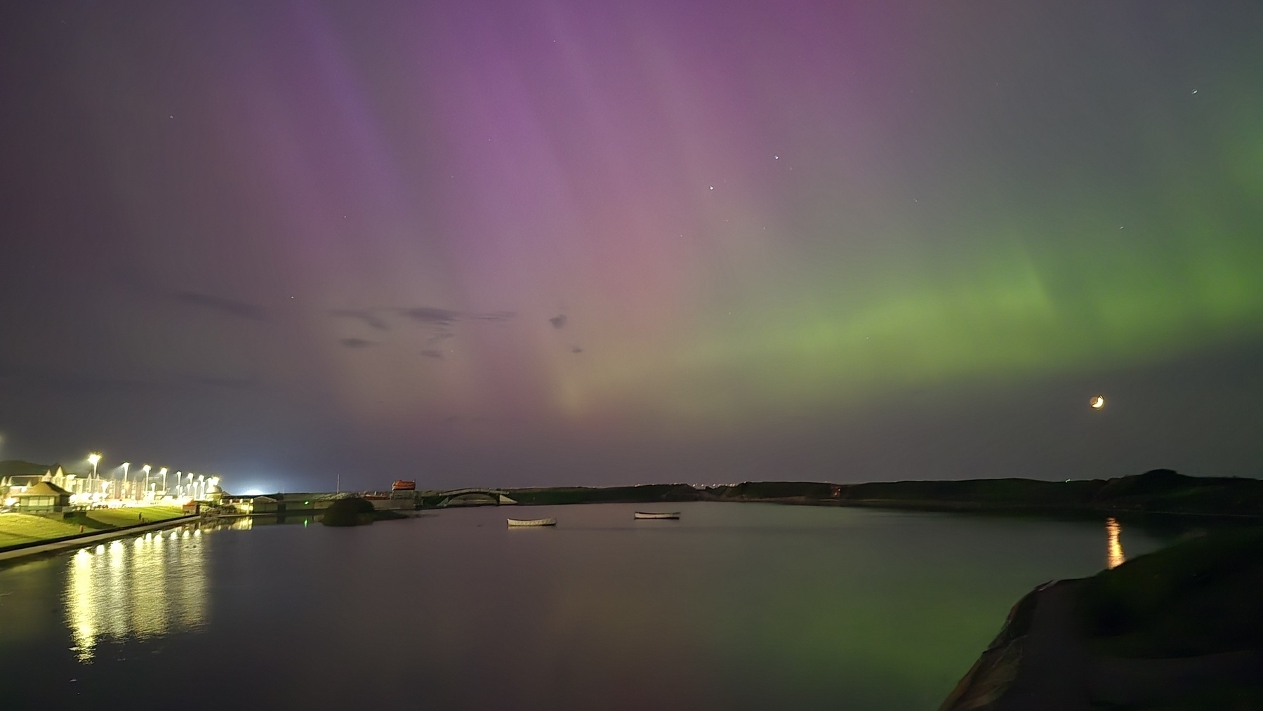 Aurora over a boating lake with green reflections in the water