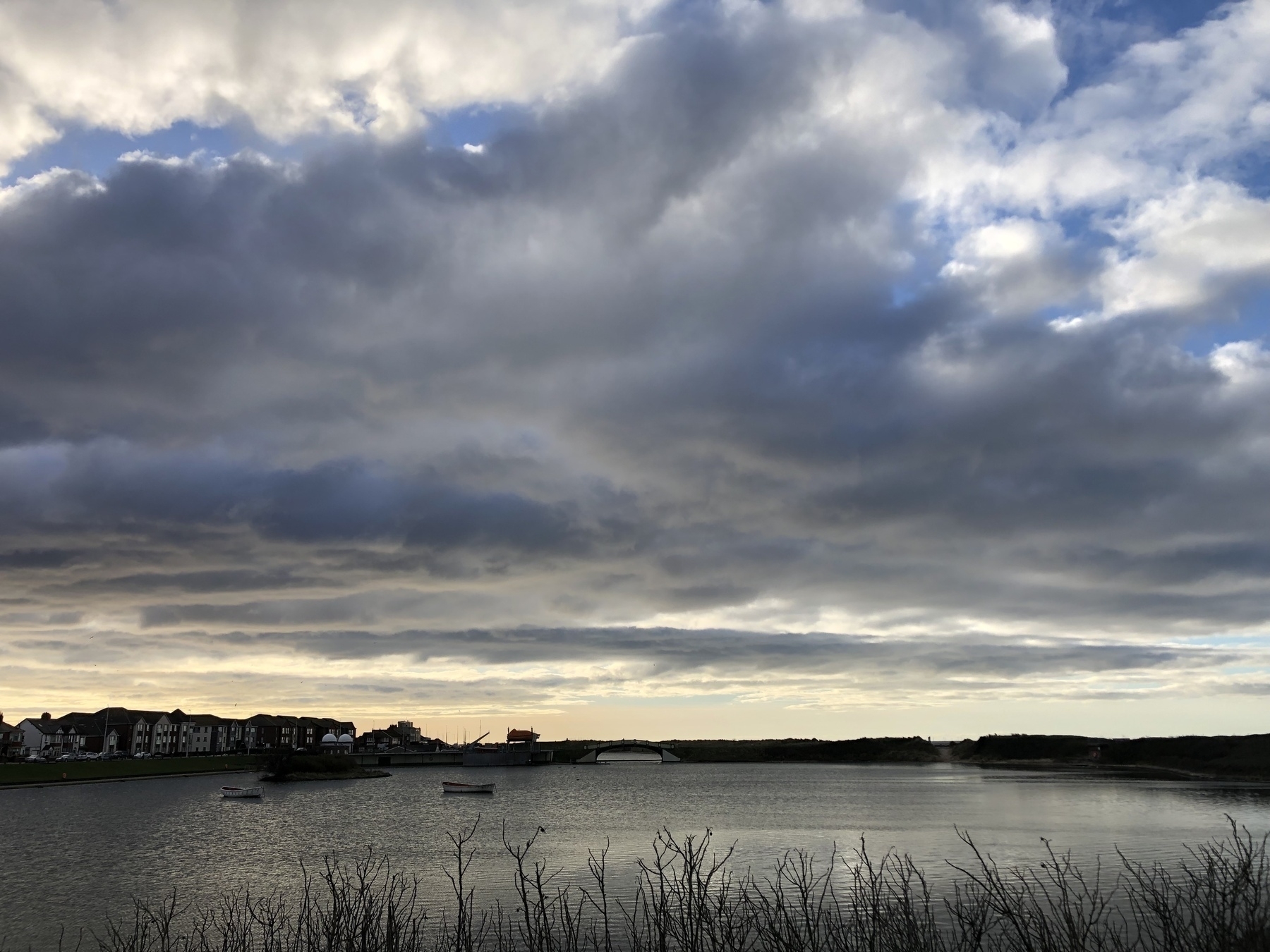 Scenic view in the afternoon with moody grey clouds and golden light peeping through and shining down over a lake