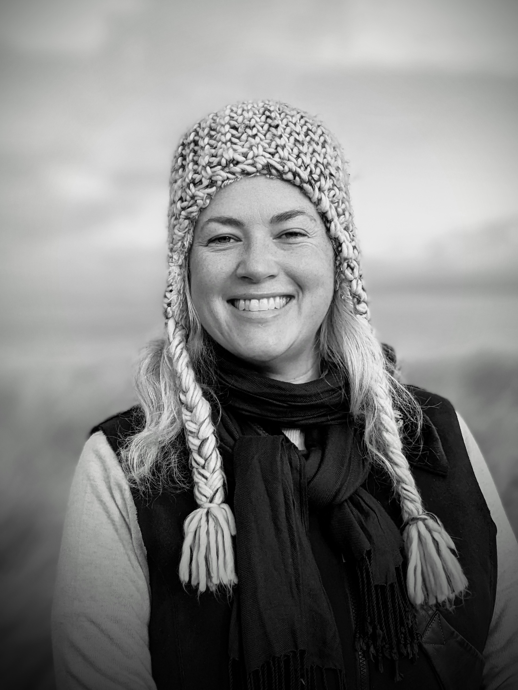 b/w portrait of me at the beach with a woolly hat on smiling at the camera