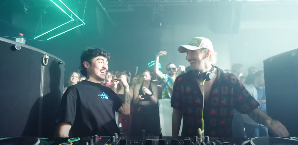 djs in a club laughing together on the decks.
