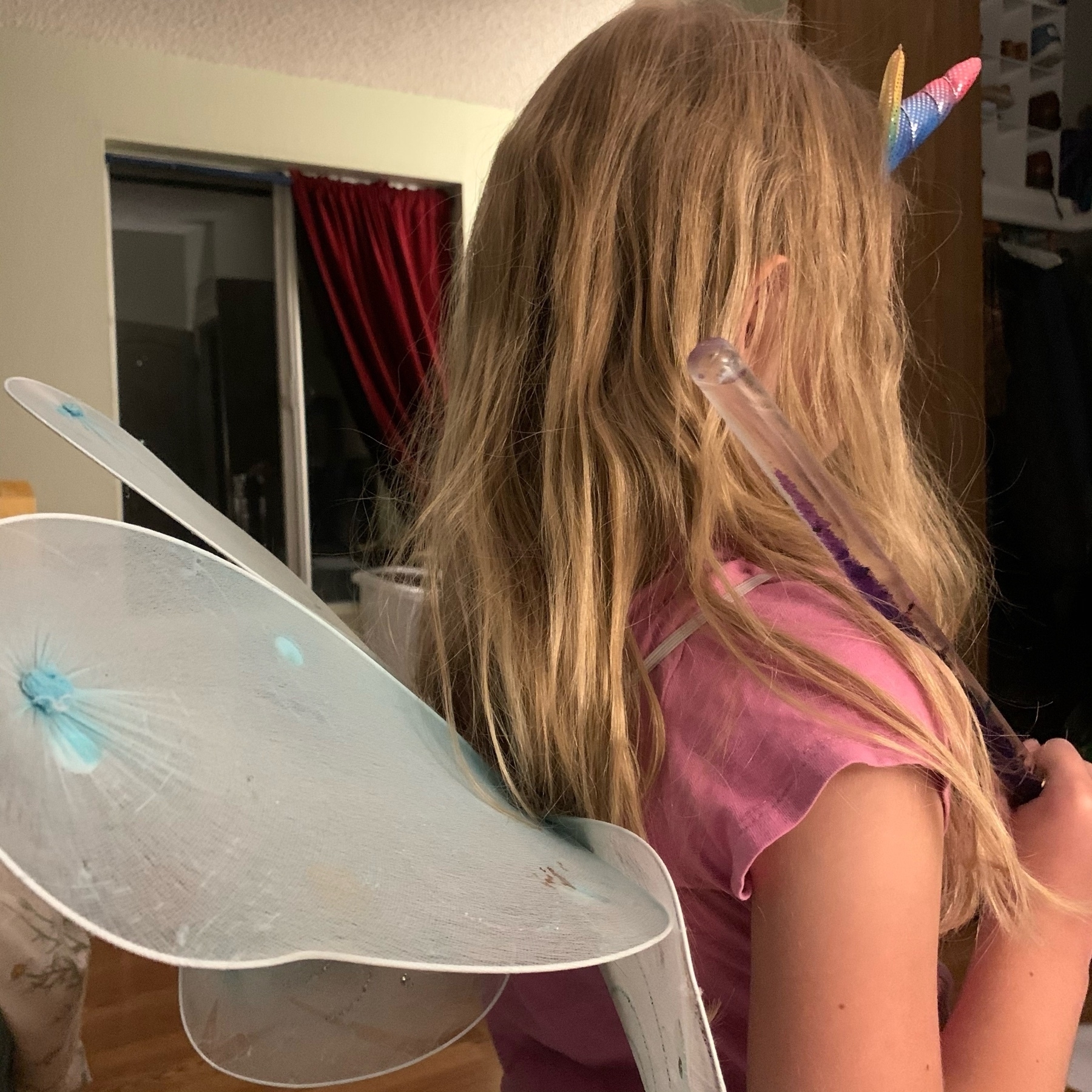 Girl holding the one while wearing wings and a unicorn headband