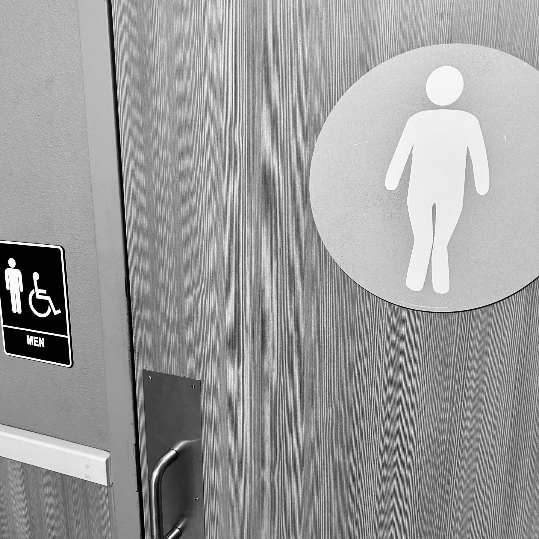 A bathroom sign of a man squeezing his knees together