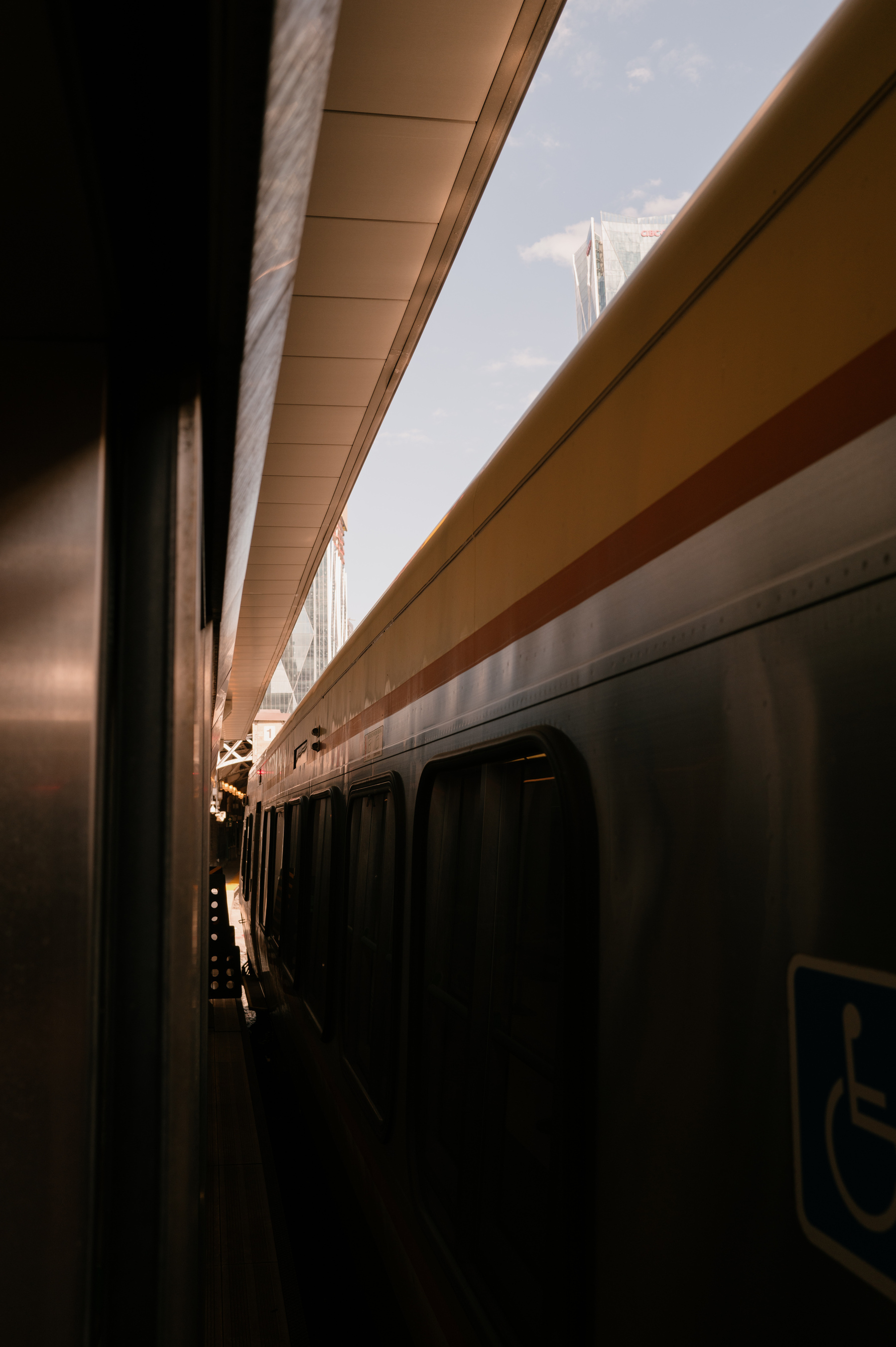 Image playing with shadows and light taken between an enclosed train track and a train shooting up into the distance. 