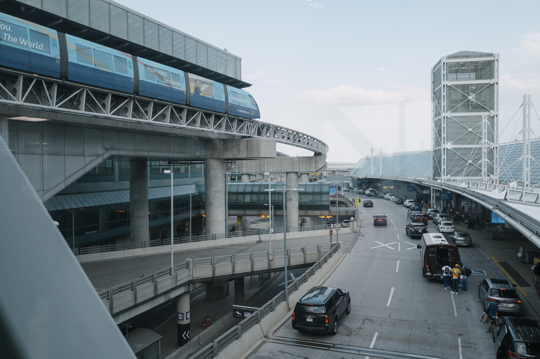 View out of a window at the Toronto Pearson International Airport, Terminal 3. It‘s overlooking the departure drop-off area and on the left the light rail can be seen. 