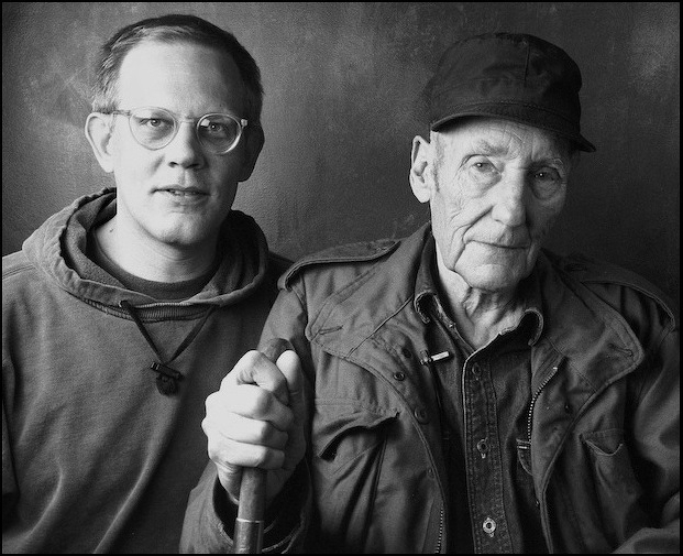 A black & white portrait of James Grauerholz and William S. Burroughs. William is in the foreground, with his hand on his cane.