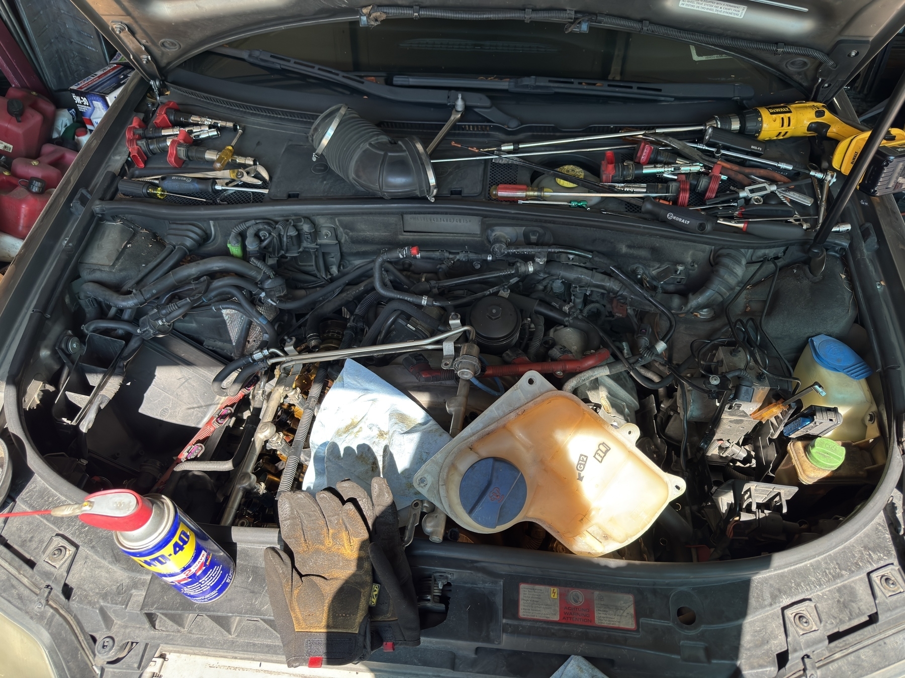 A C5 allroad 4.2 V8 engine compartment littered with tools and with only one valve cover removed.