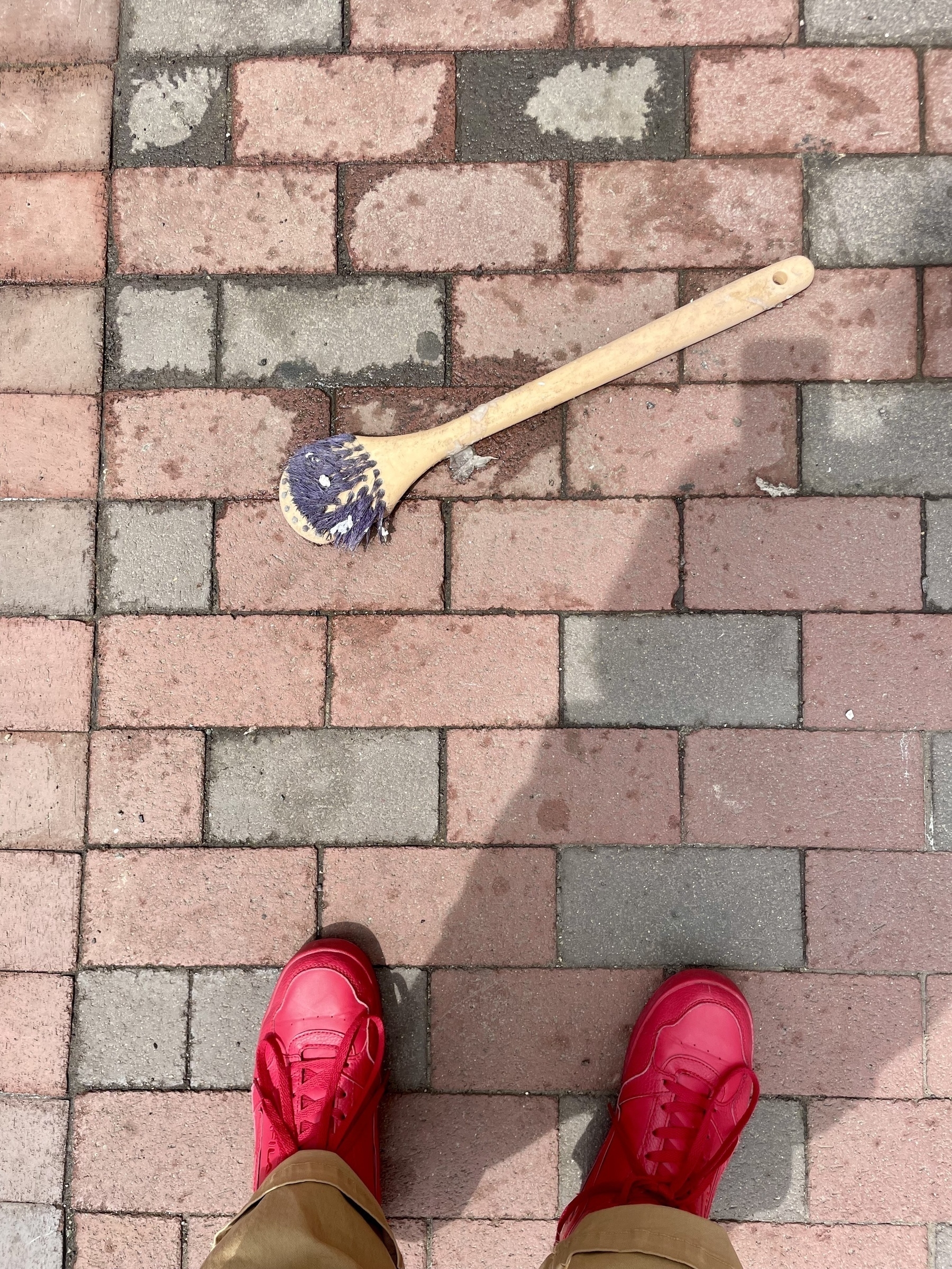 A shower brush on the brick sidewalk, its bristles smashed to oblivion