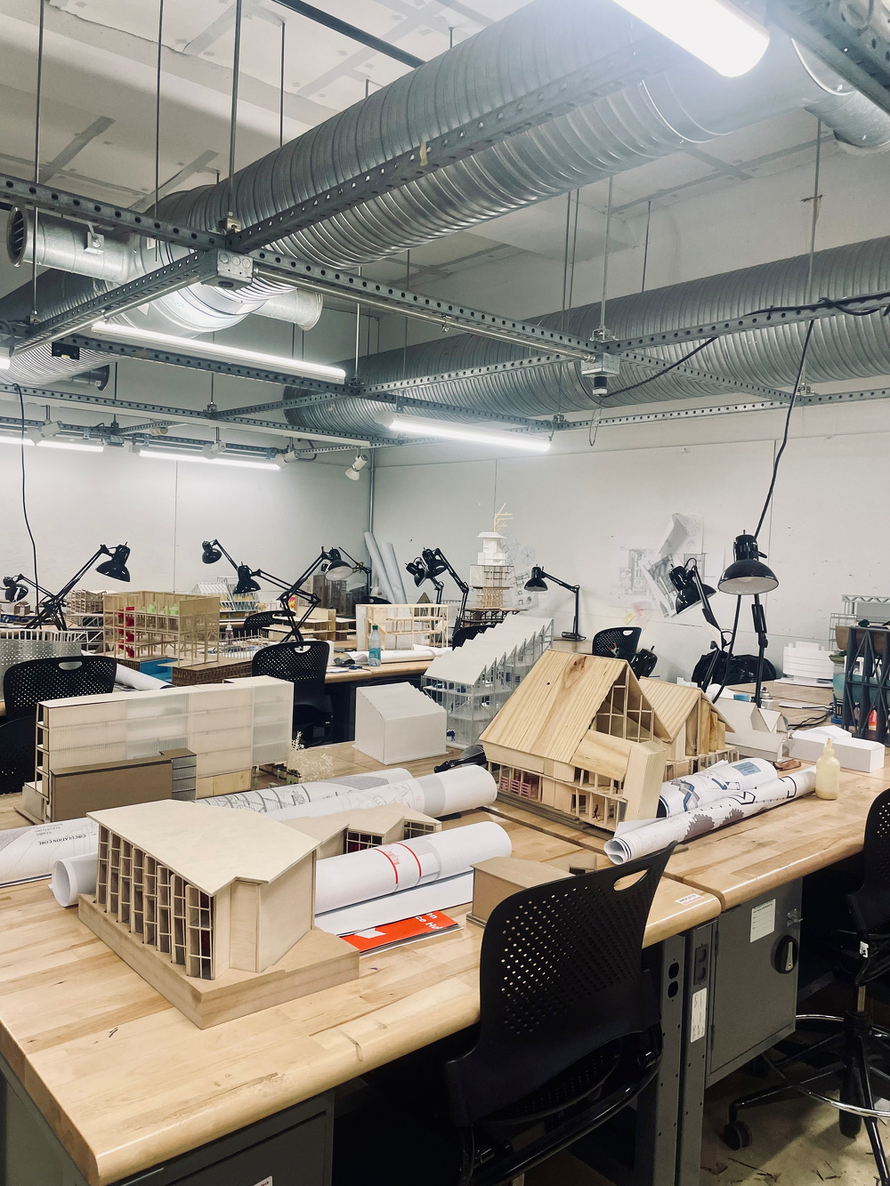 A medium shot of the architecture desks where student models and detritus sit