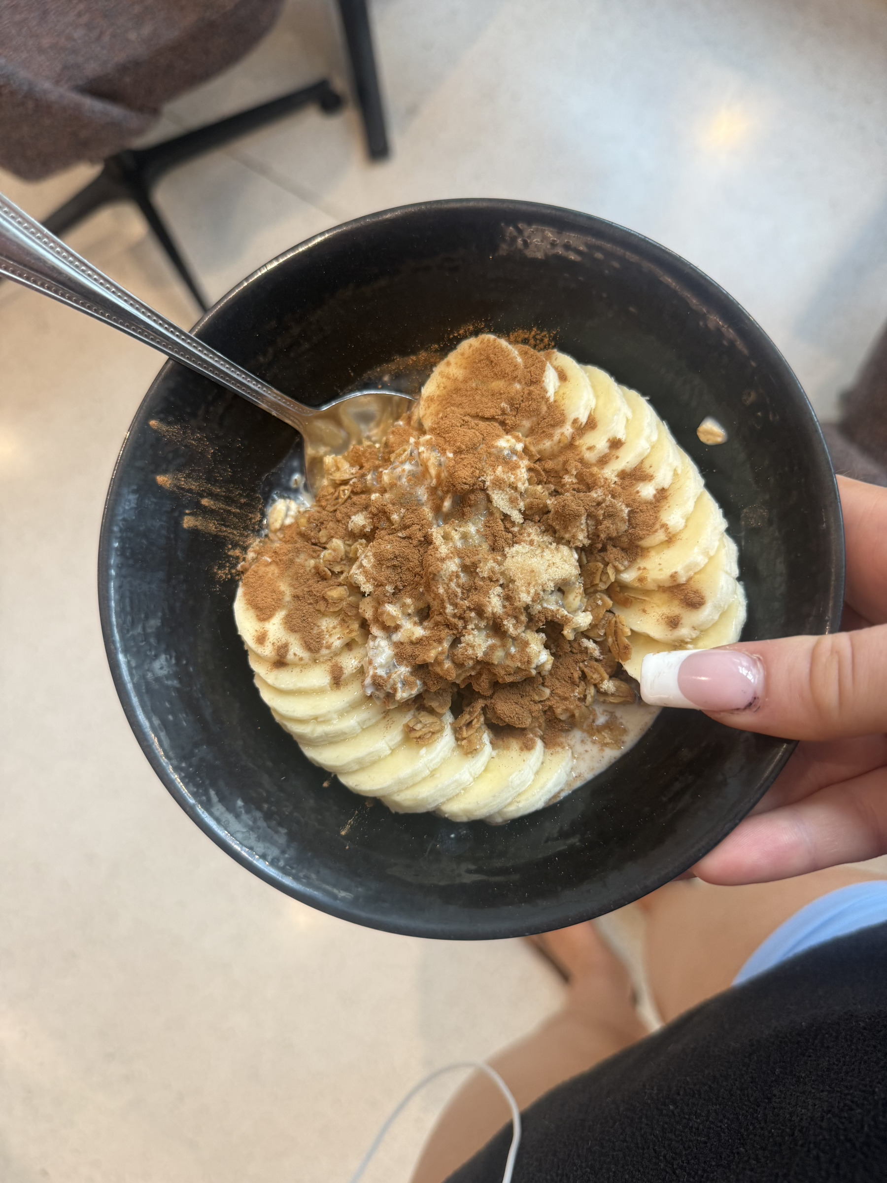 A bowl of oatmeal with bananas beautifully arrayed in a fan pattern on the top, sprinkled with cinnamon