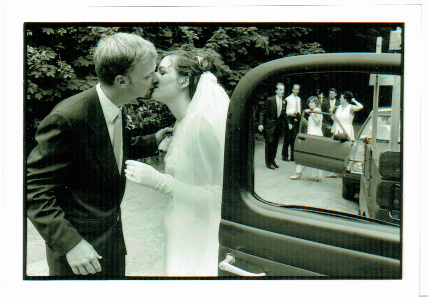A black and white photo of Brian and me in our wedding attire, kissing just before we leave the church in an antique truck