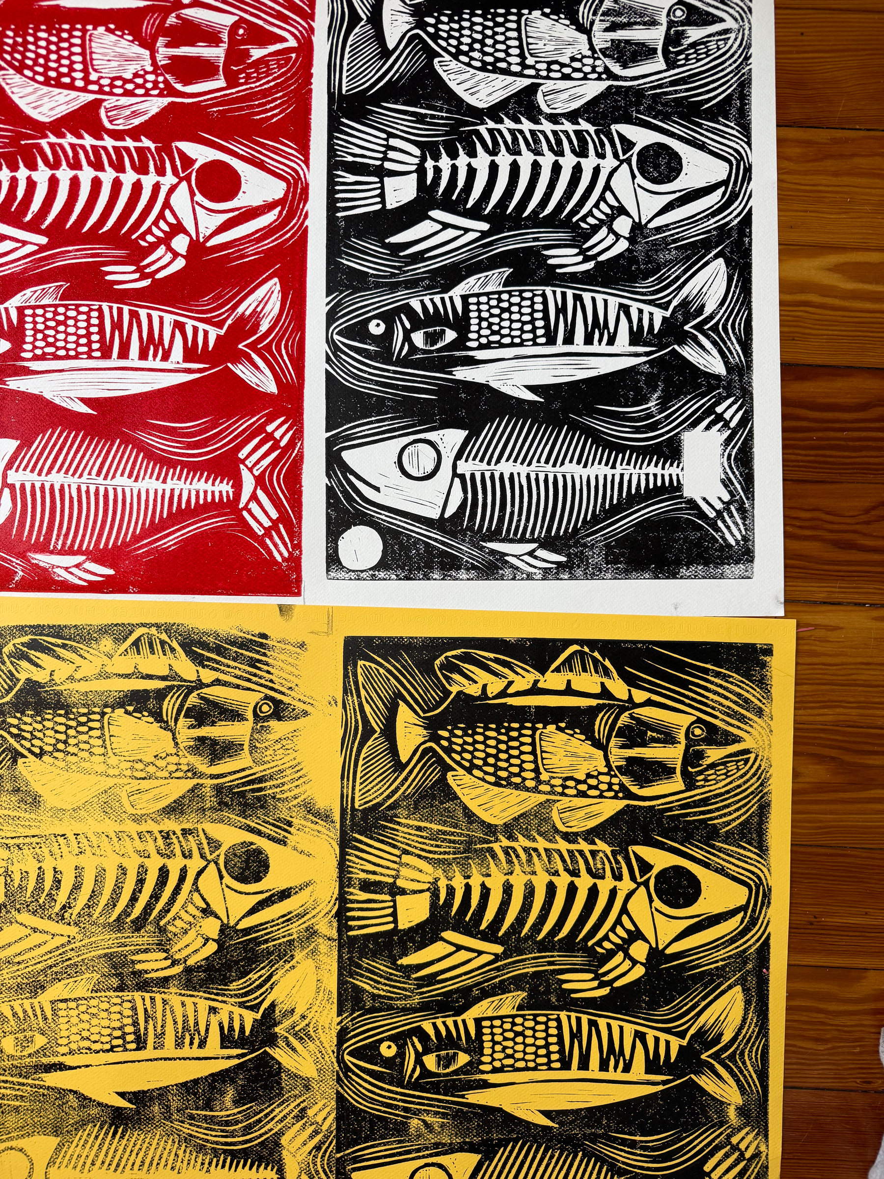 A grid of four lino cut prints, one each on white and red and two on yellow, the same pattern of four rush, some whole and some skeletal.
