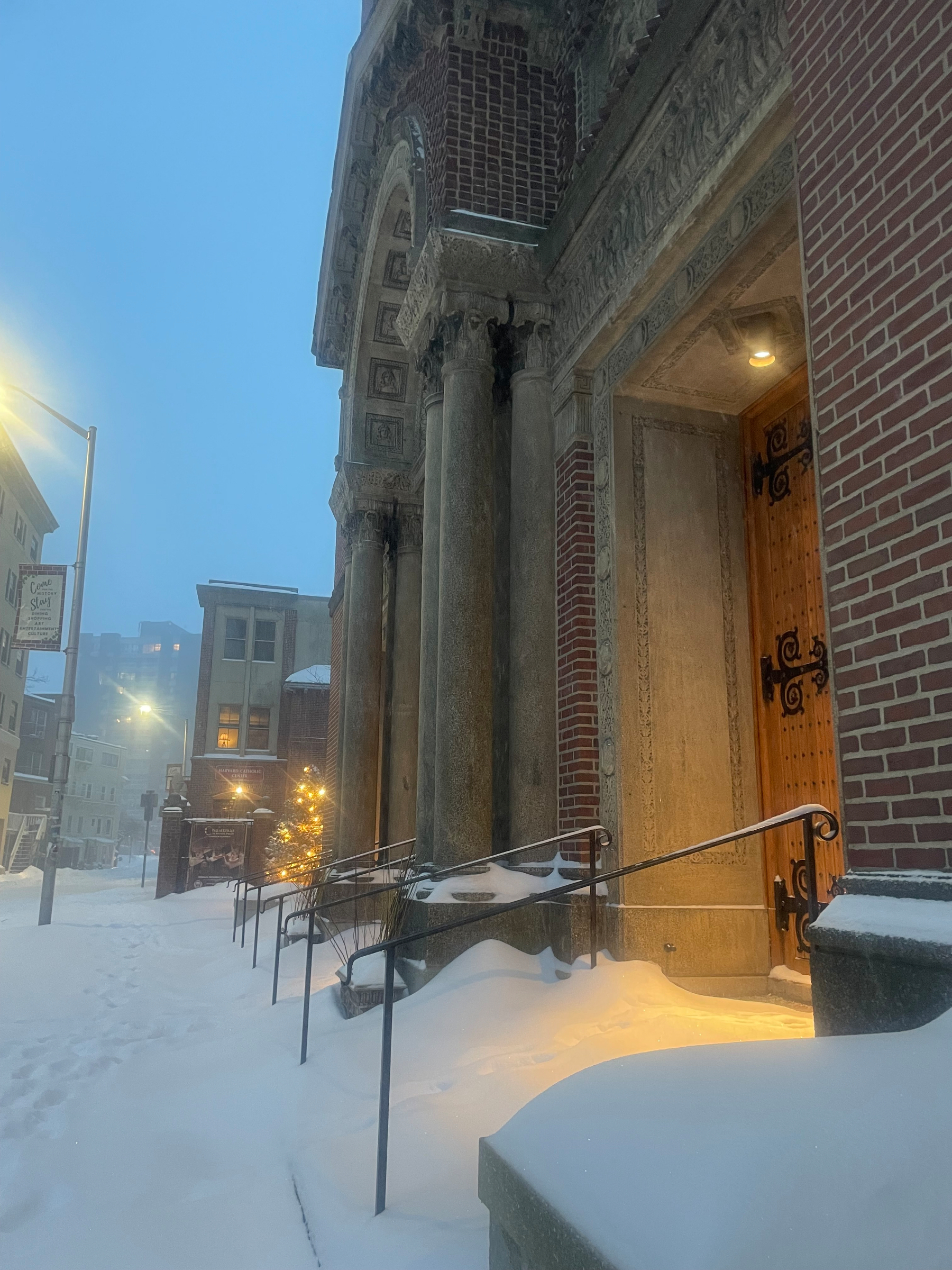 In a blizzard, the entrance of a church welcomes with its warm light.