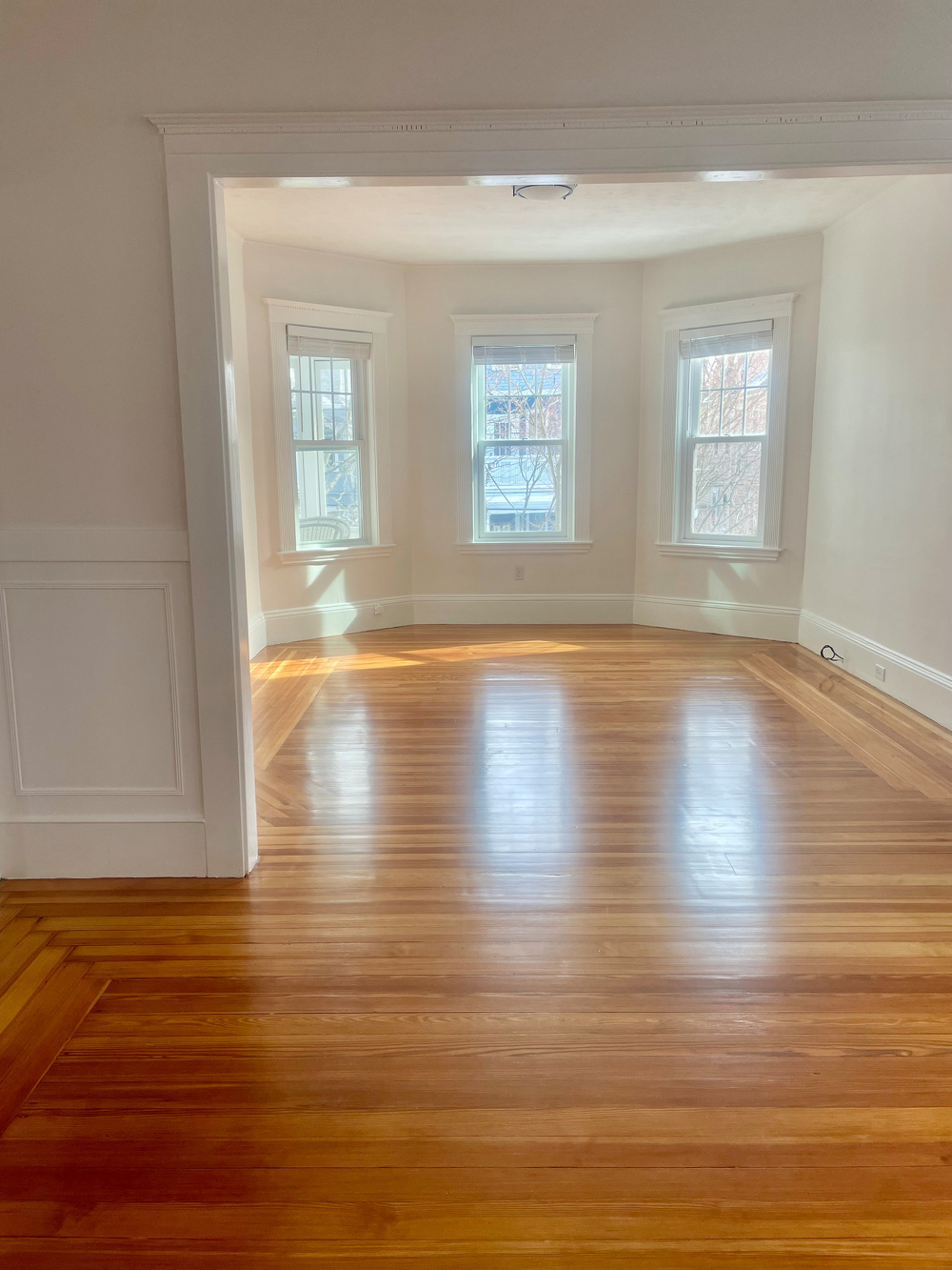 Our bare living room and dining room, gleaming white walls and wood floors.