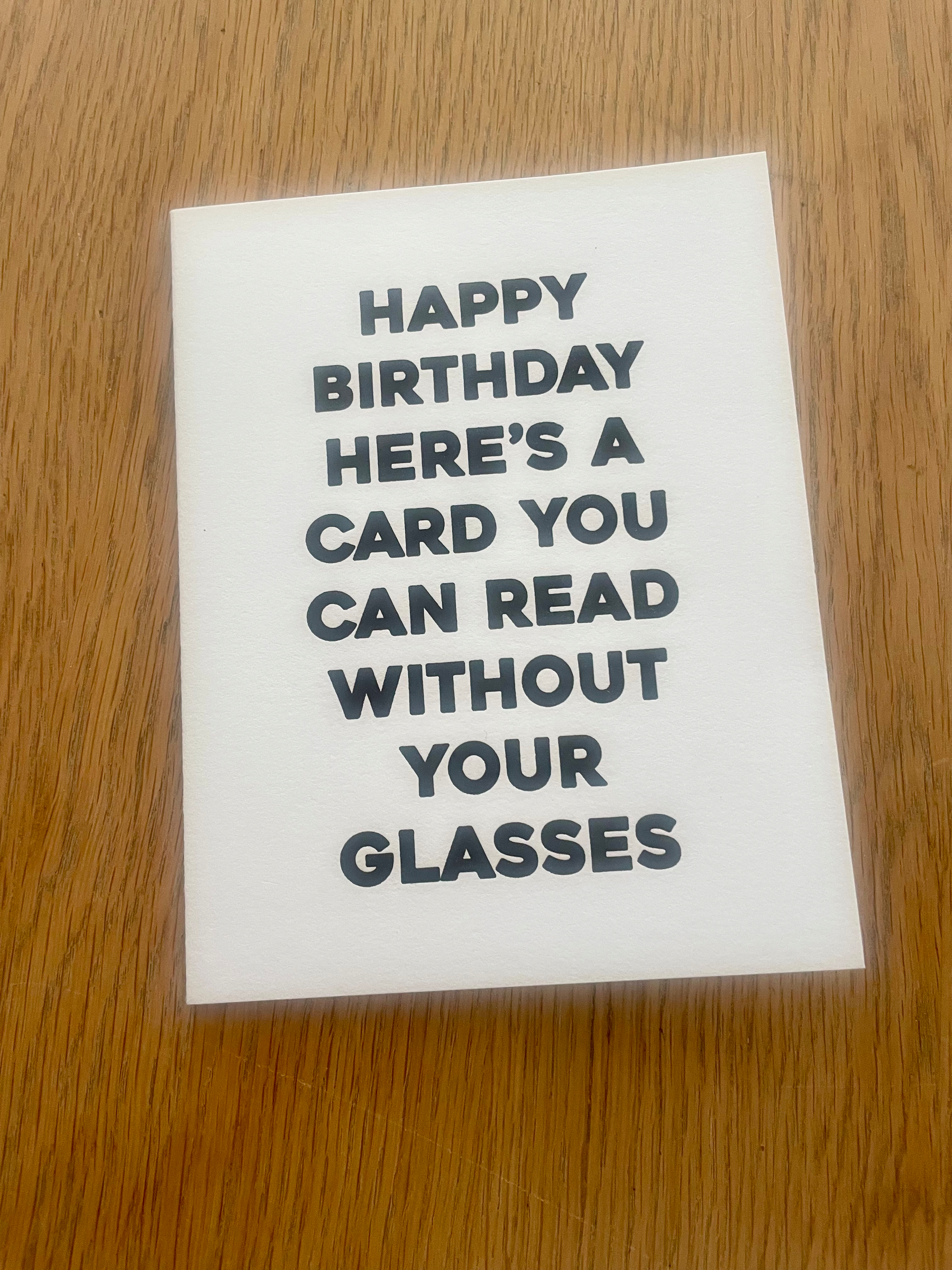 A white card has thick black lettering that reads: Happy Birthday; here’s a card you can read without your glasses.