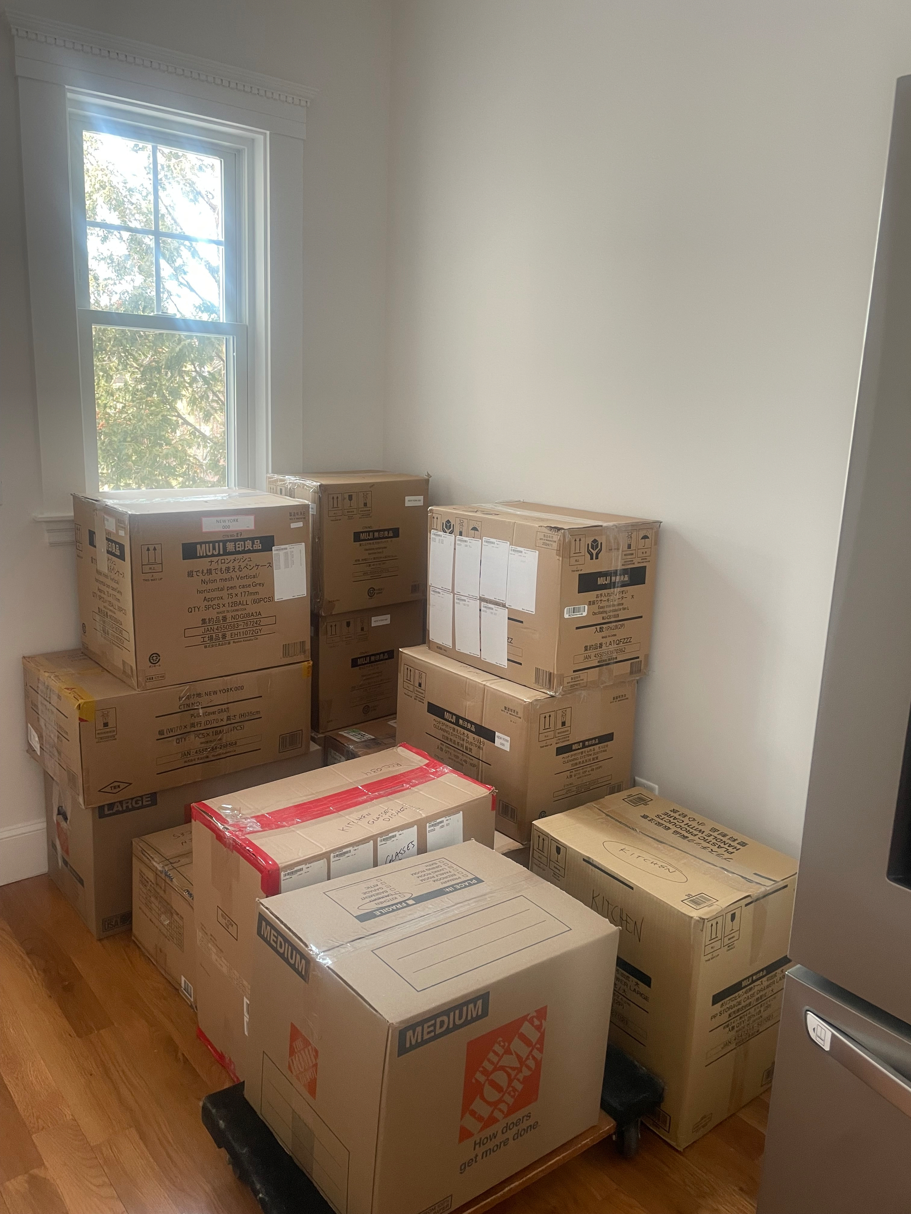 A bunch of moving boxes by a wall in our old apartment, ready to head out
