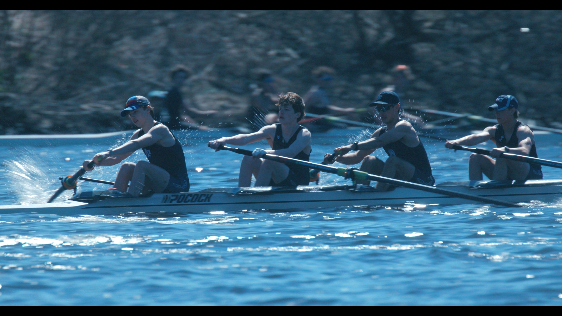 In a four-person boat, young men row the Charles River.