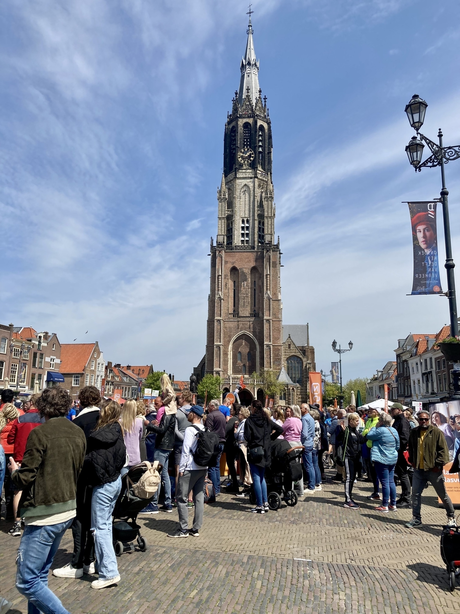 marktplein in Delft vol met mensen, met op de achtergrond de toren van de Nieuwe Kerk