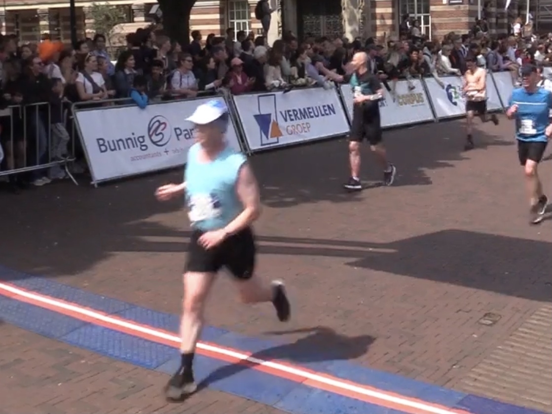 wazige foto van hardloper in blauw mouwloos shirt die de finishlijn passeert