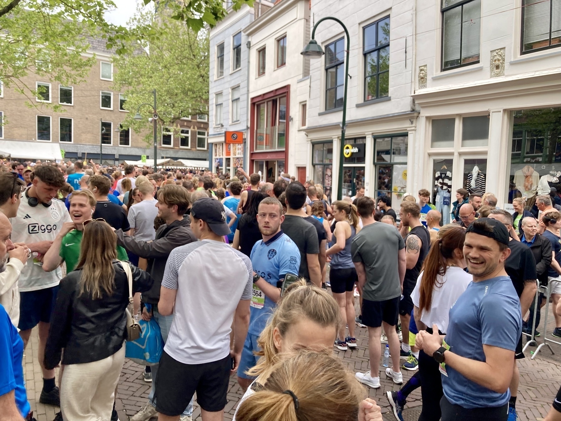 Een menigte mensen, van wie velen atletische kleding dragen, hebben zich verzameld en staan te wachten op het startschot van de 10 km wedstrijd, op de Brabantse Turfmarkt in Delft.