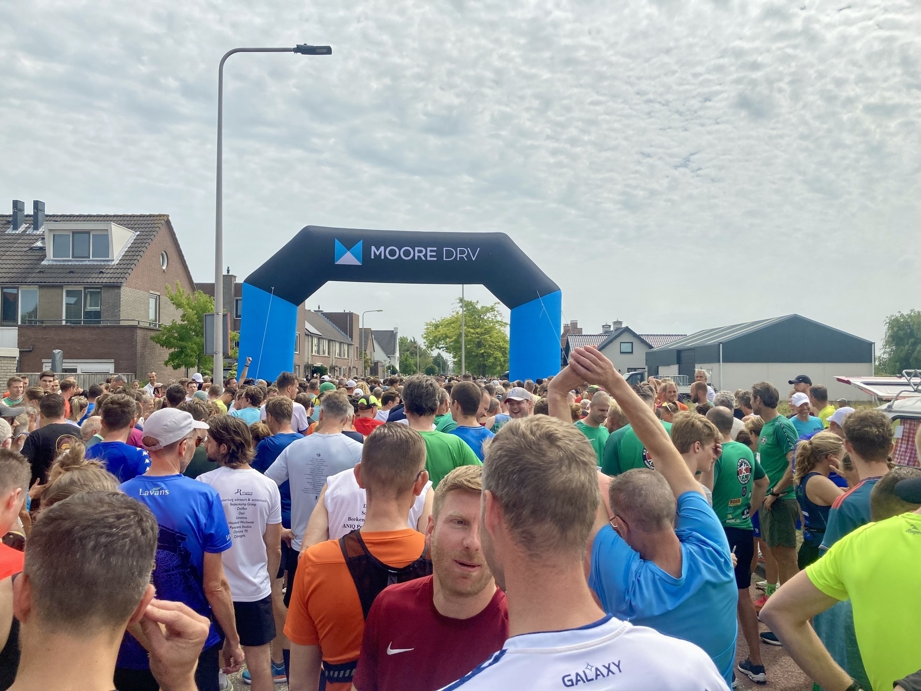 Een grote menigte mensen is verzameld onder een opblaasbare boog op een buitenevenement.