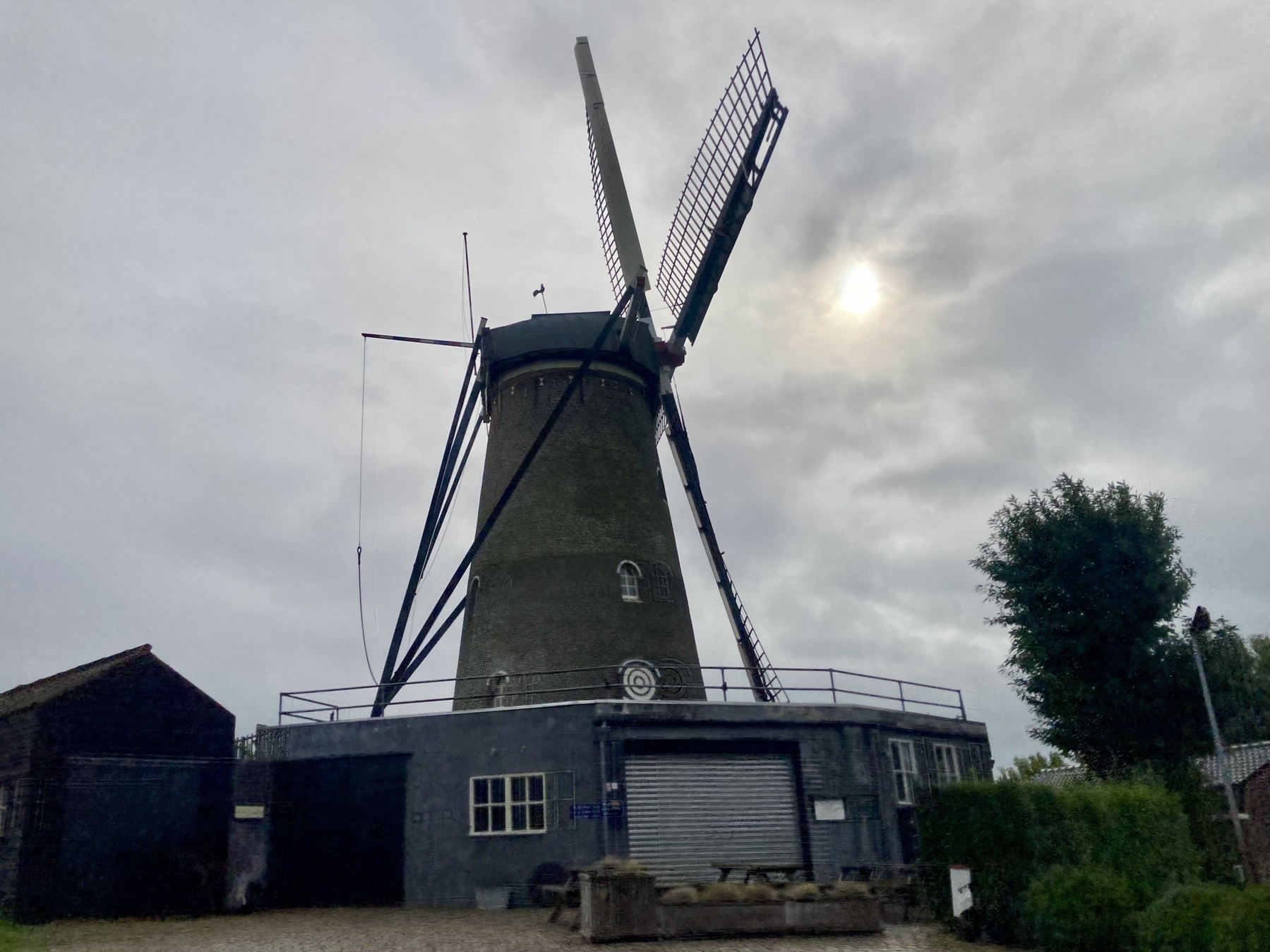 Sombere molen tegen een herfstachtige lucht, met een waterige zon en vol met wolken
