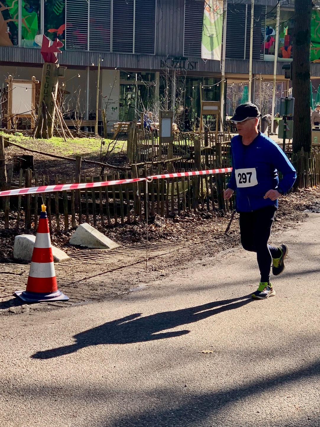 Een hardloper met het nummer 297 neemt deel aan een buitenrace, met oranje kegels die het pad markeren.