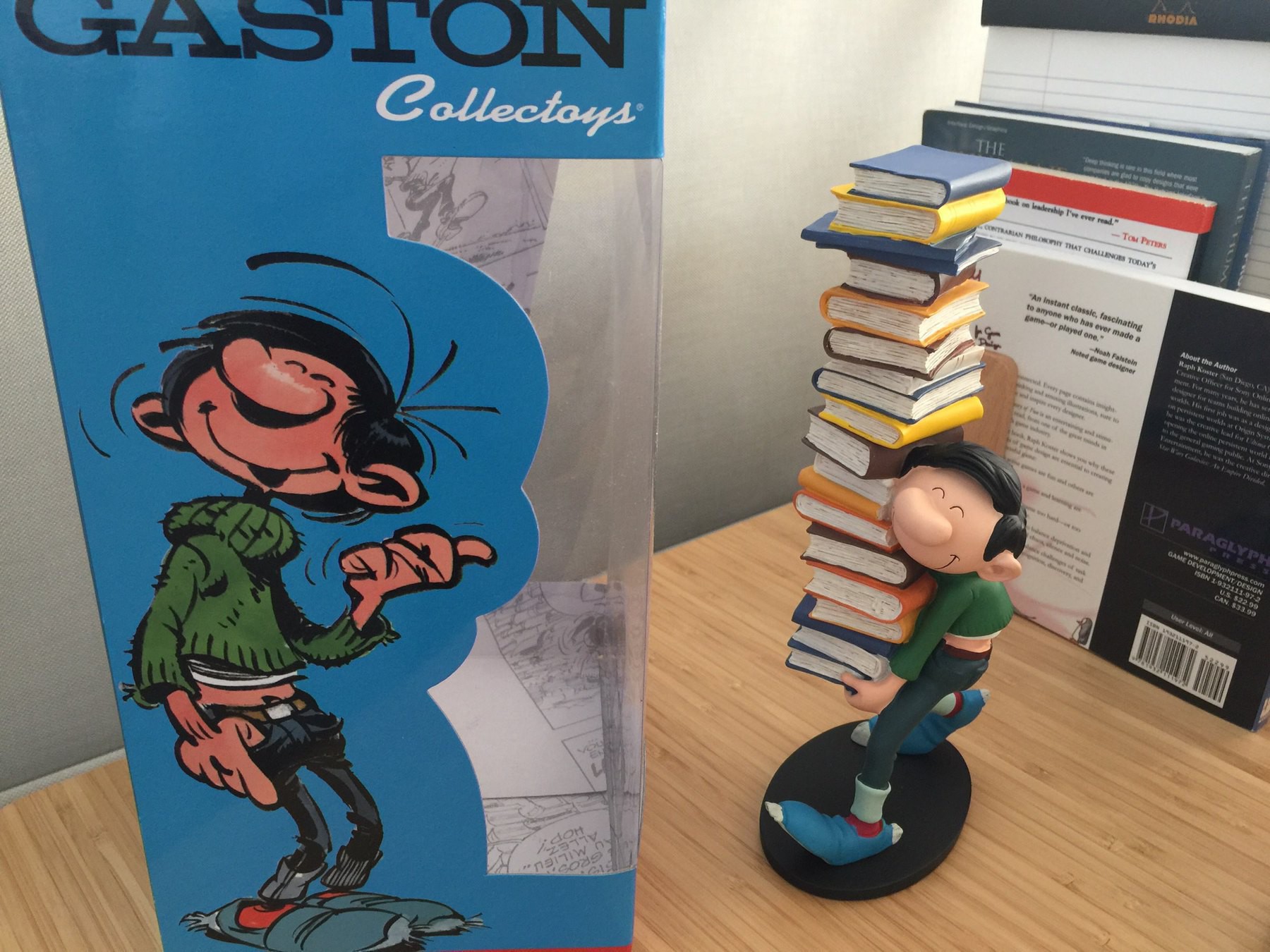 A resin statuette of Gaston Lagaffe carrying a pile of books.