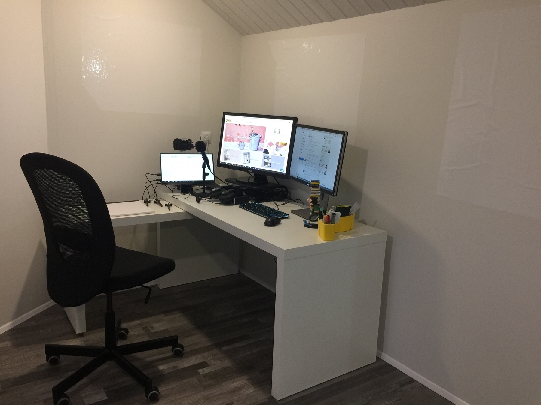 a white desk with three monitors in a corner